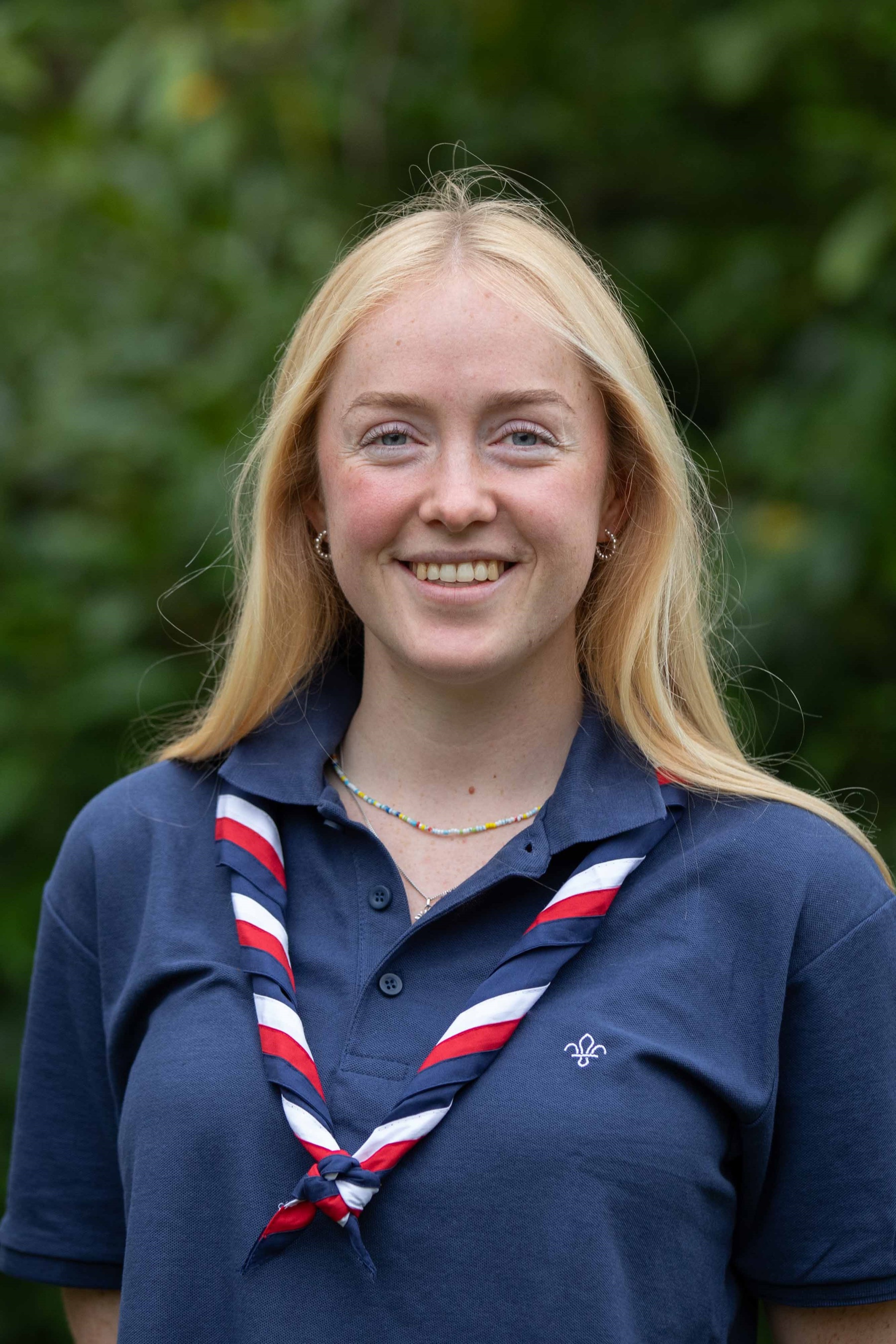 Charlotte, wearing a navy polo and red, white and blue necker, smiles at the camera.