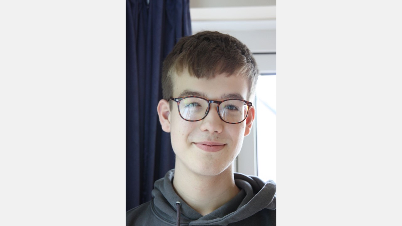 A young person wearing glasses and smiling