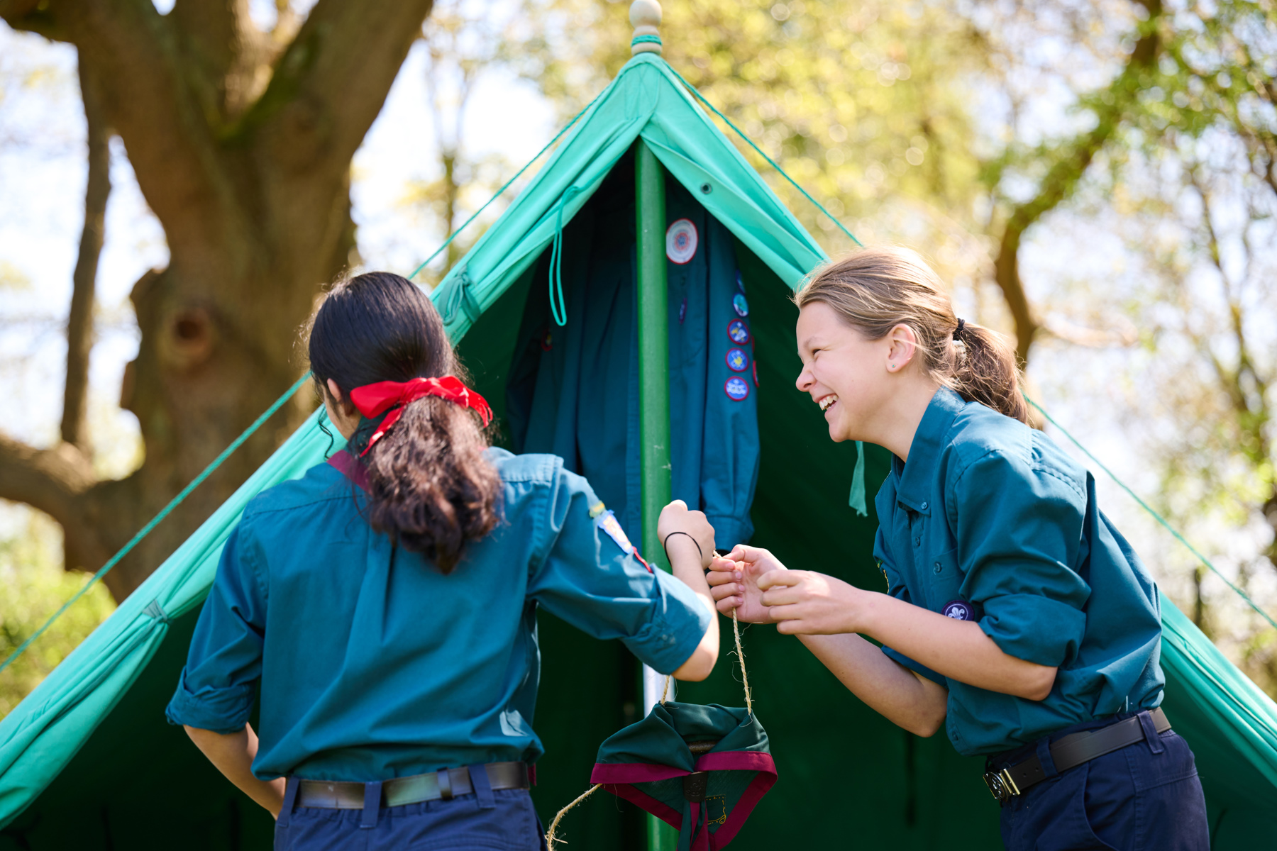 Two scouts putting up a patrol tent wearing their uniforms