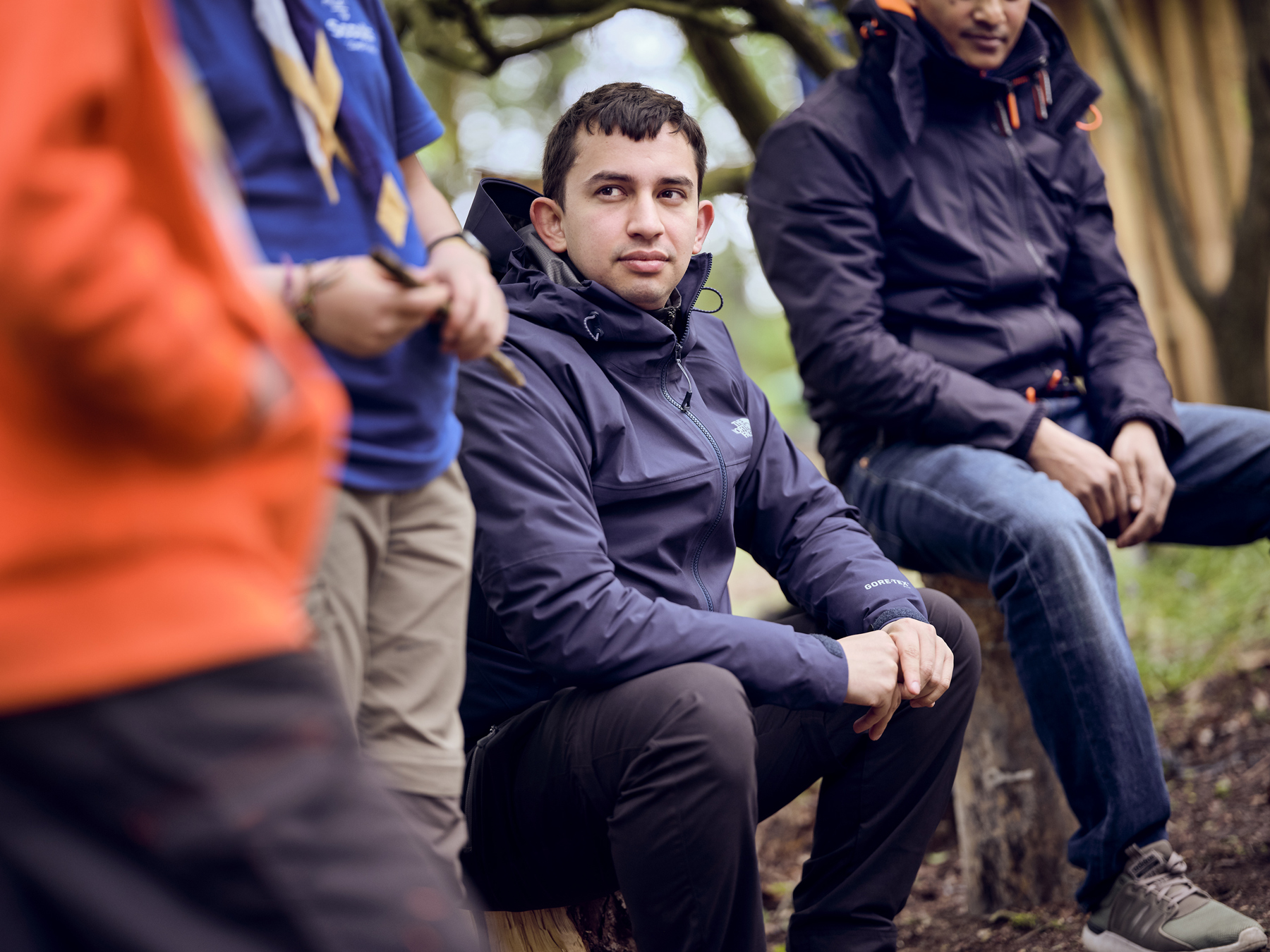 A volunteer sits down in a circle of other volunteers outside.