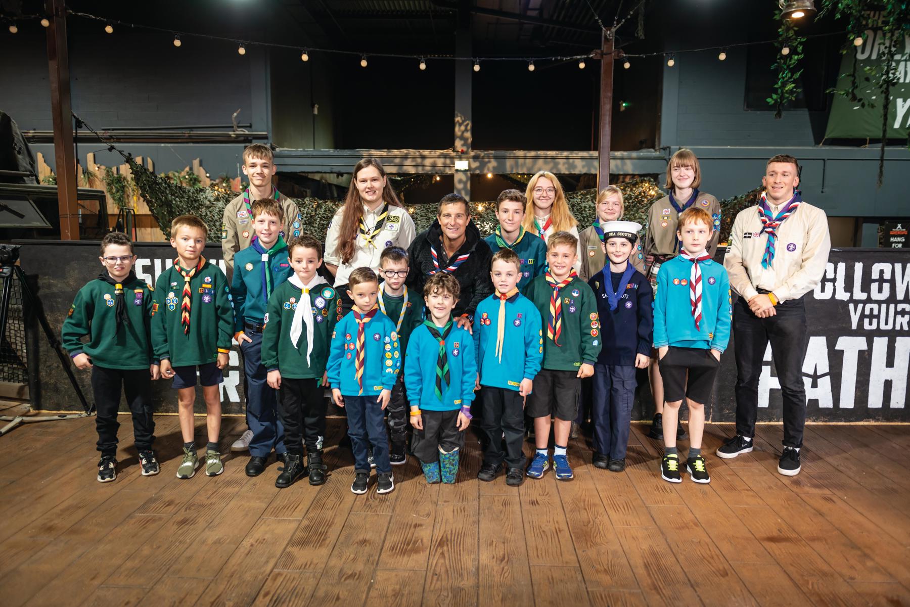A group of Beavers sanding with Bear Grylls
