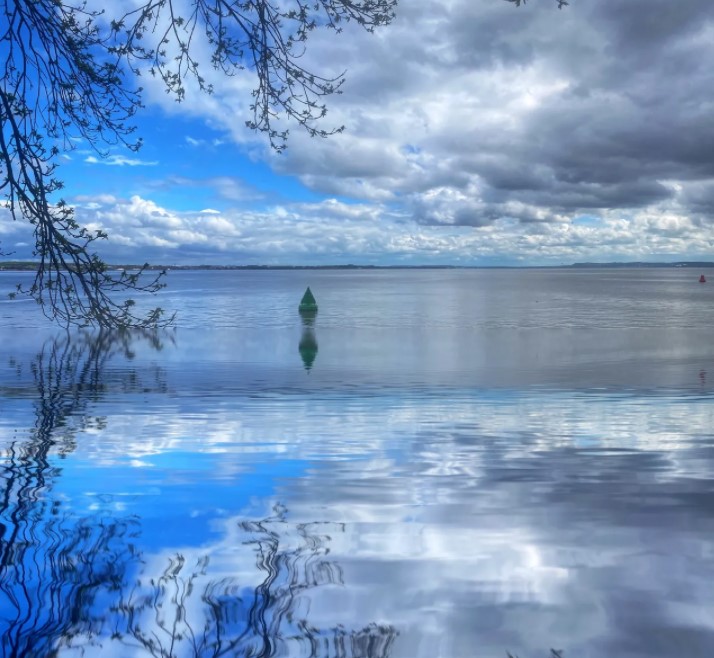 A large body of still water with bright blue sky and white clouds above