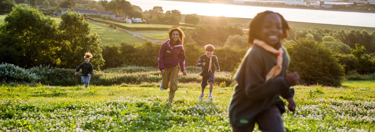 Cub Scouts and a leader running in a field