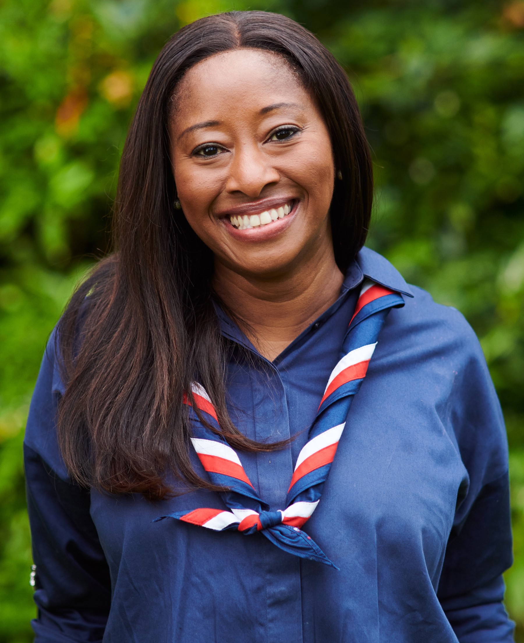 Busola Sodeinde smiling at the camera wearing a navy shirt and stripy scarf