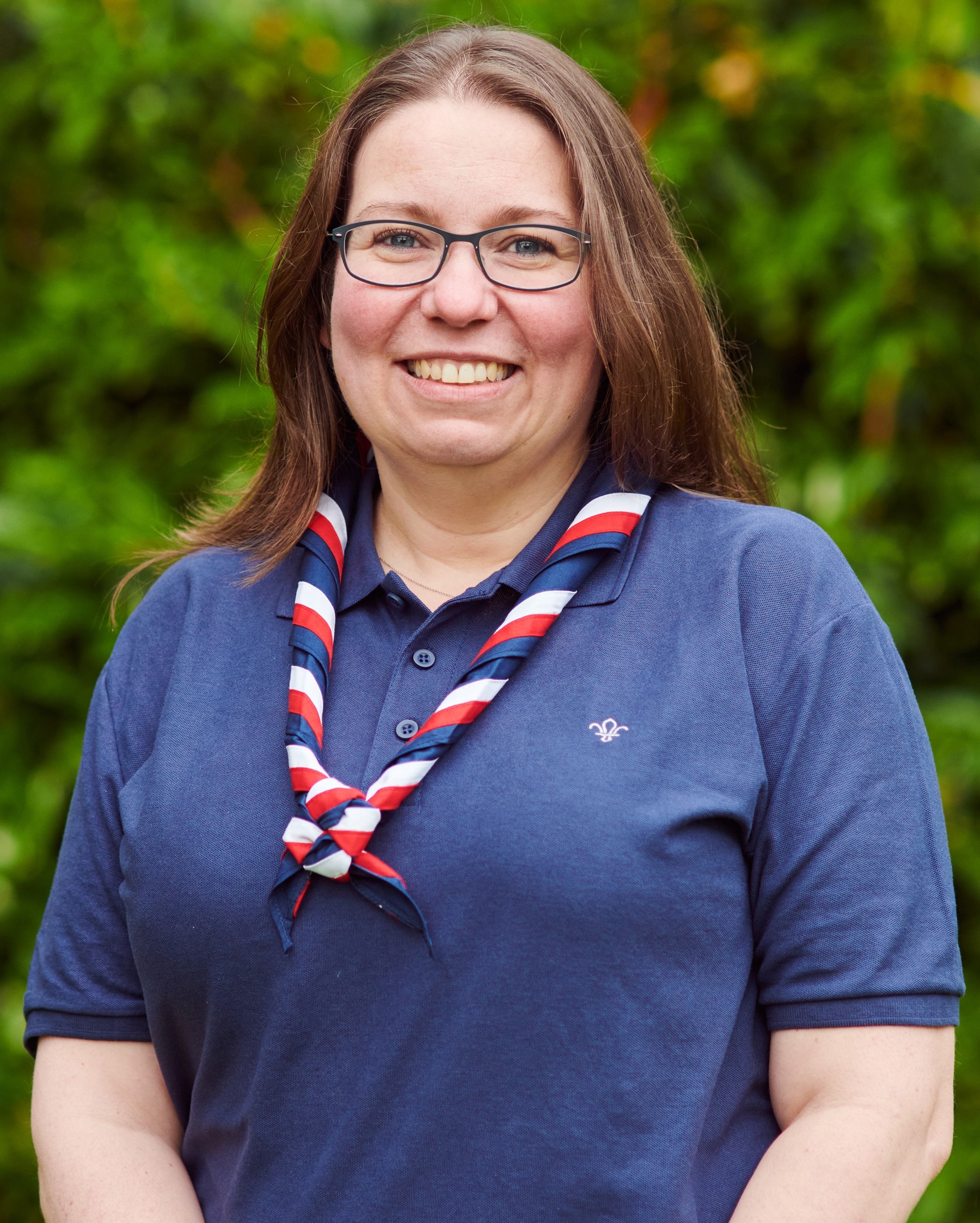 CJ Ledger smiling at the camera while wearing a navy Scouts polo shirt and stripy scarf