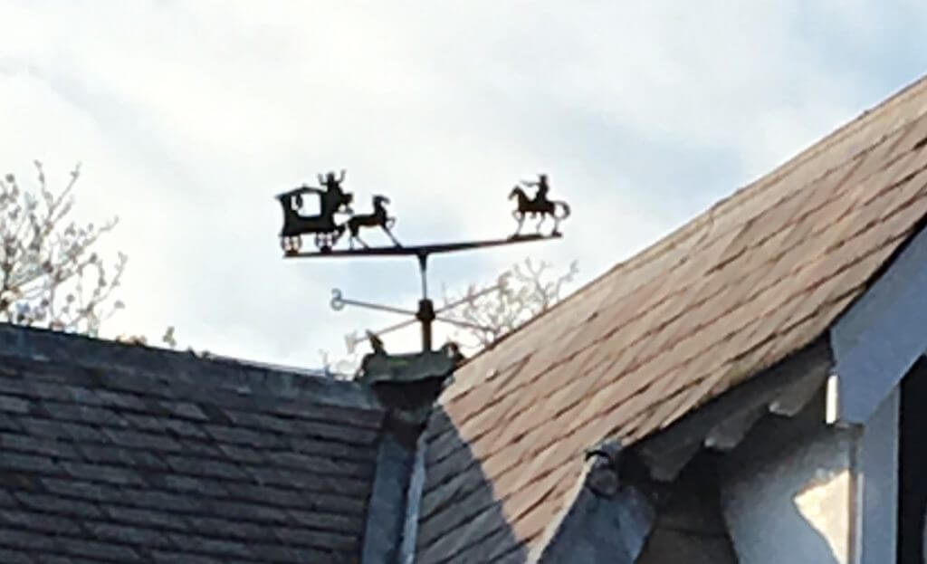 Image shows a weathervane depiction of Dick Turpin on horseback holding up a horse and carriage
