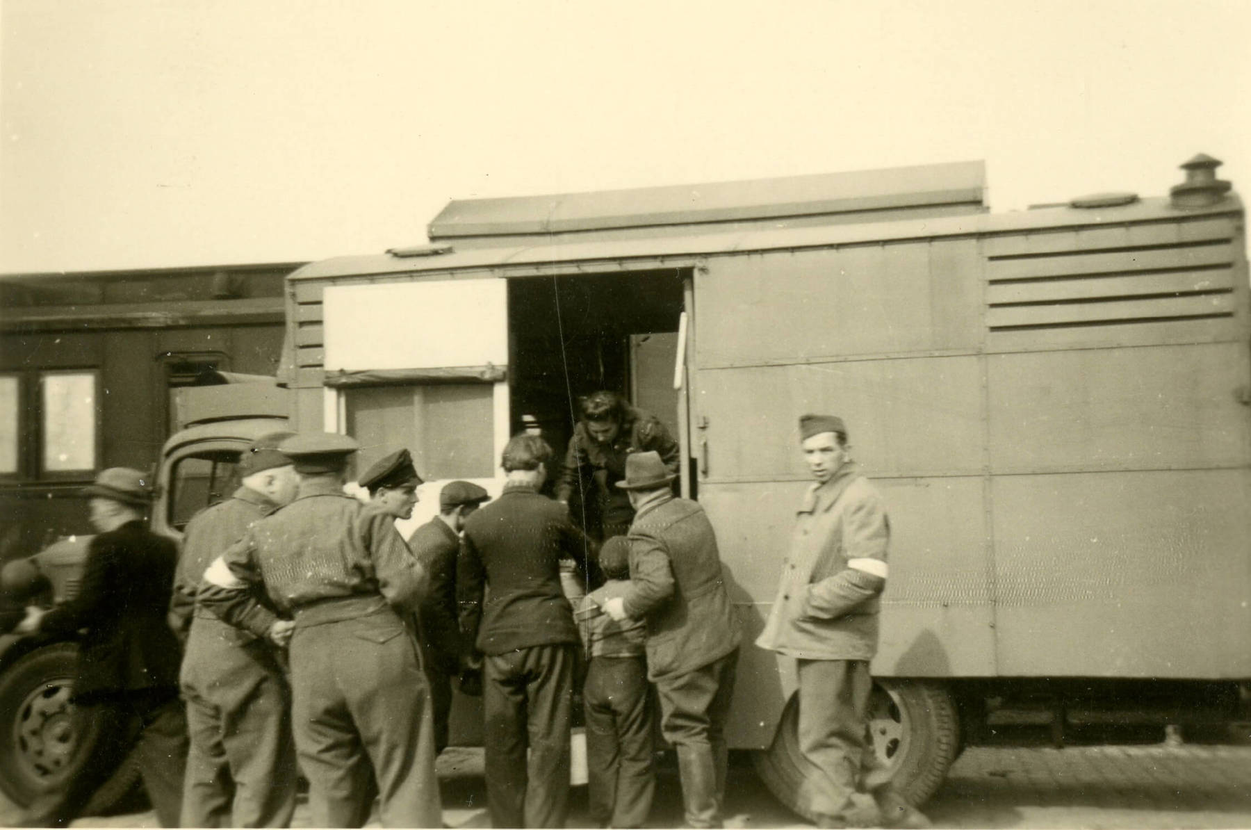 Black and white photo of a group of people accompanying Polish displaced person onto a train