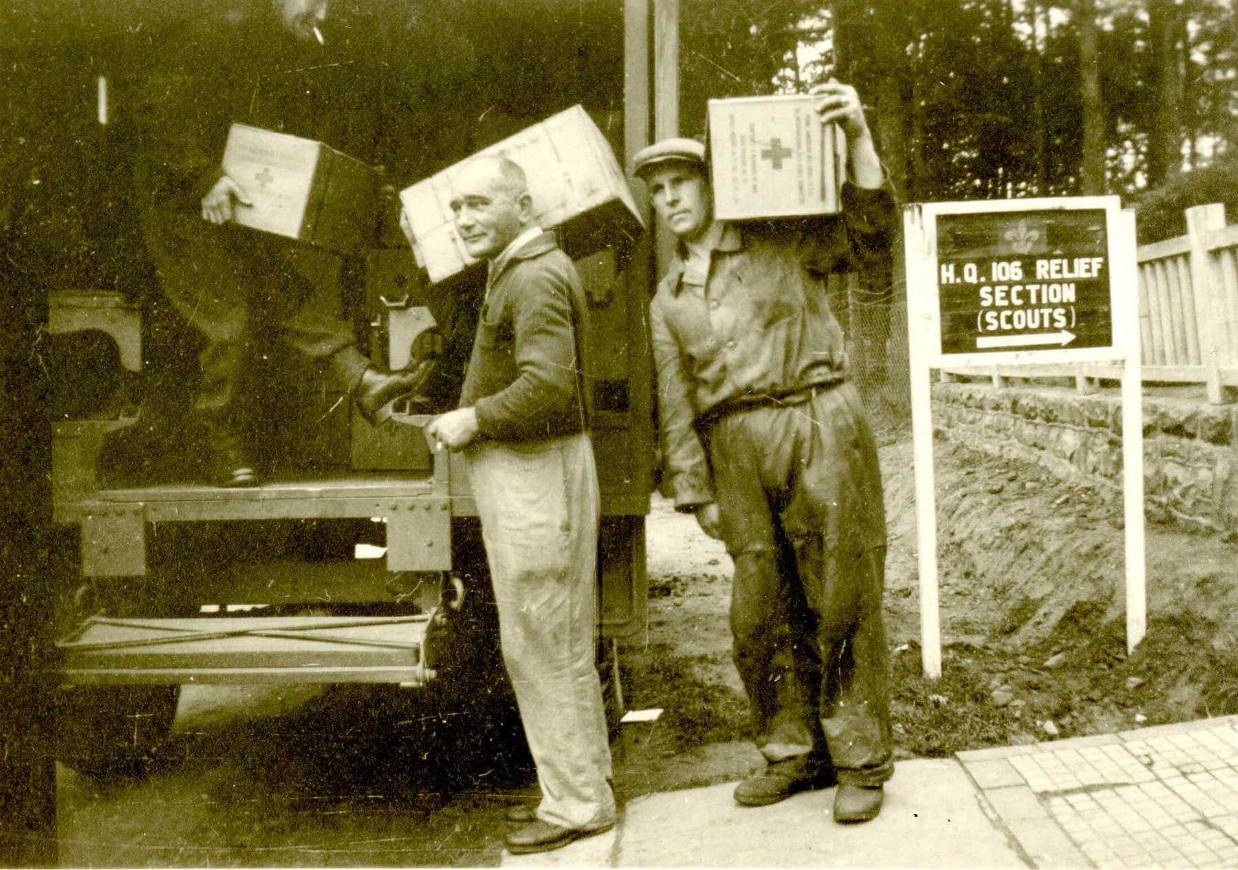 Black and white photo of three men unloading parcels from the back of a van