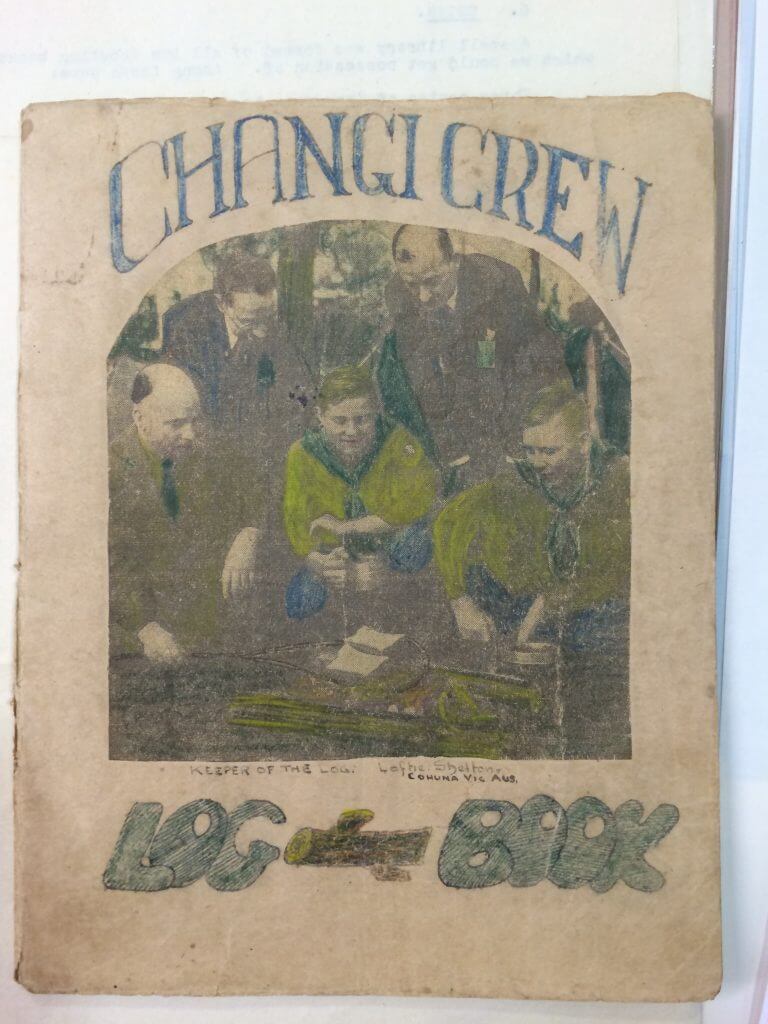 A faded book titled 'Changi Crew Log Book', with an illustration of two Scouts with three adults
