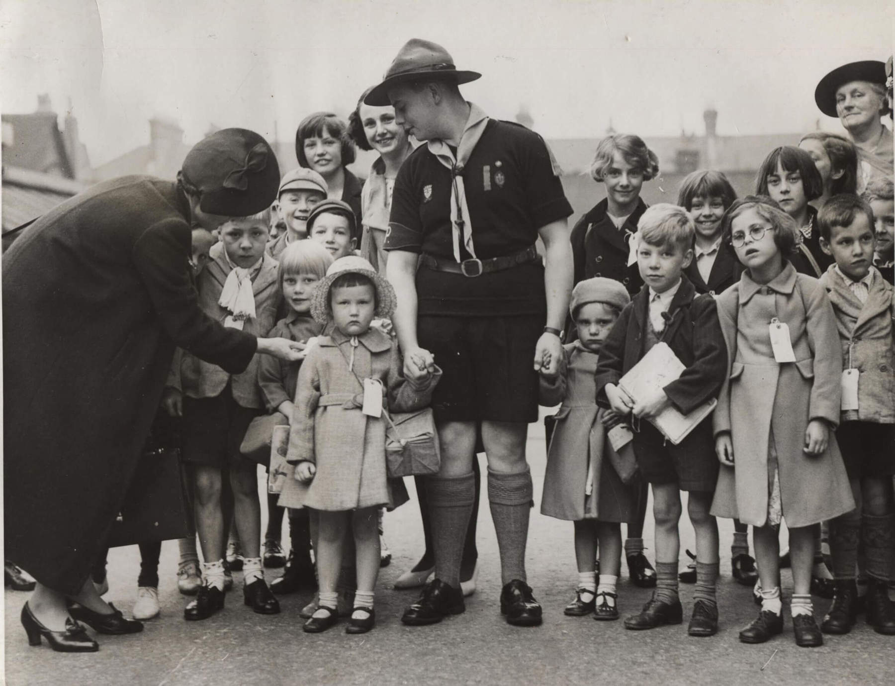 Black and white photo of a Scout holding hands with a group of young people