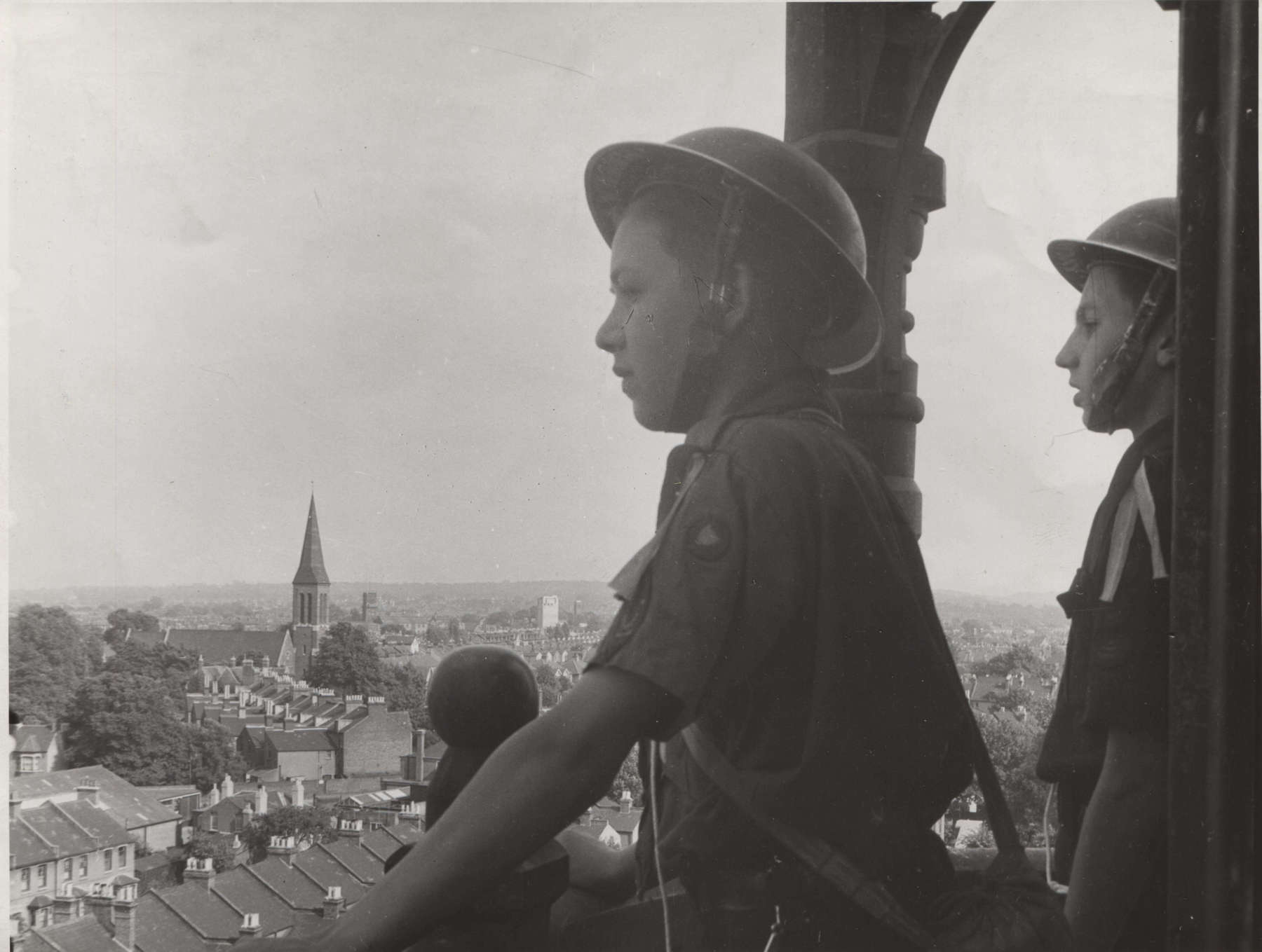 Black and white photo of two Scouts standing on top of a high building watching over the town