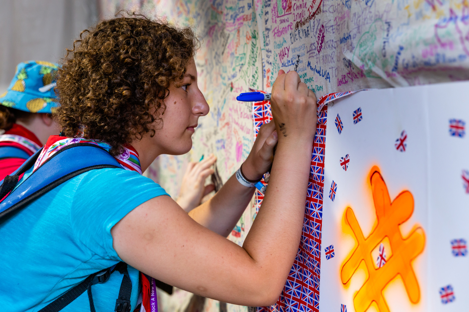 An Explorer writes a message on a wall covered in UK flags.