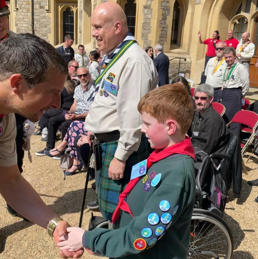 Bear Grylls shakes the hand of Louis Jackson, who is wearing Scout uniform with lots of badges, at Windsor