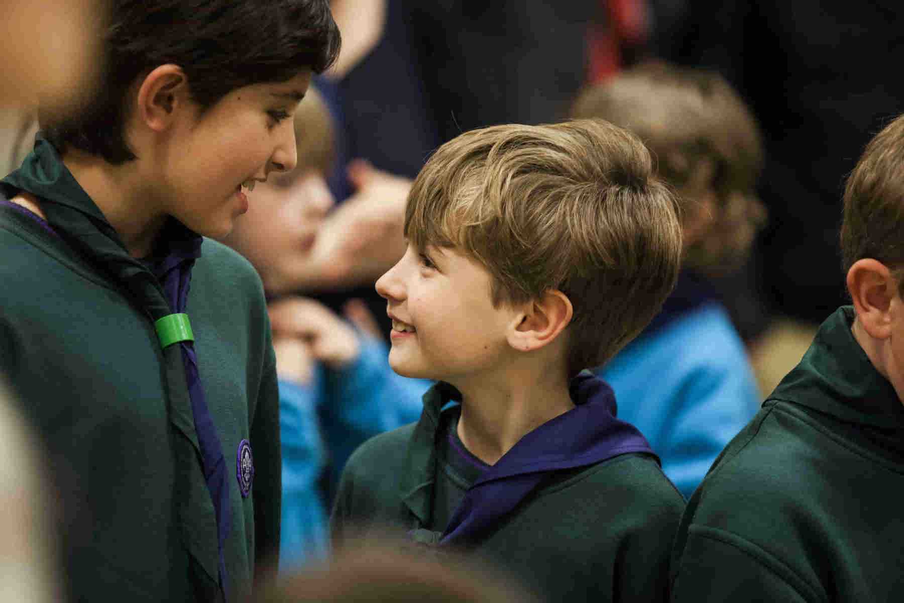 Two boys chatting at a Cub group wearing their green cub uniform, scarf and woggles