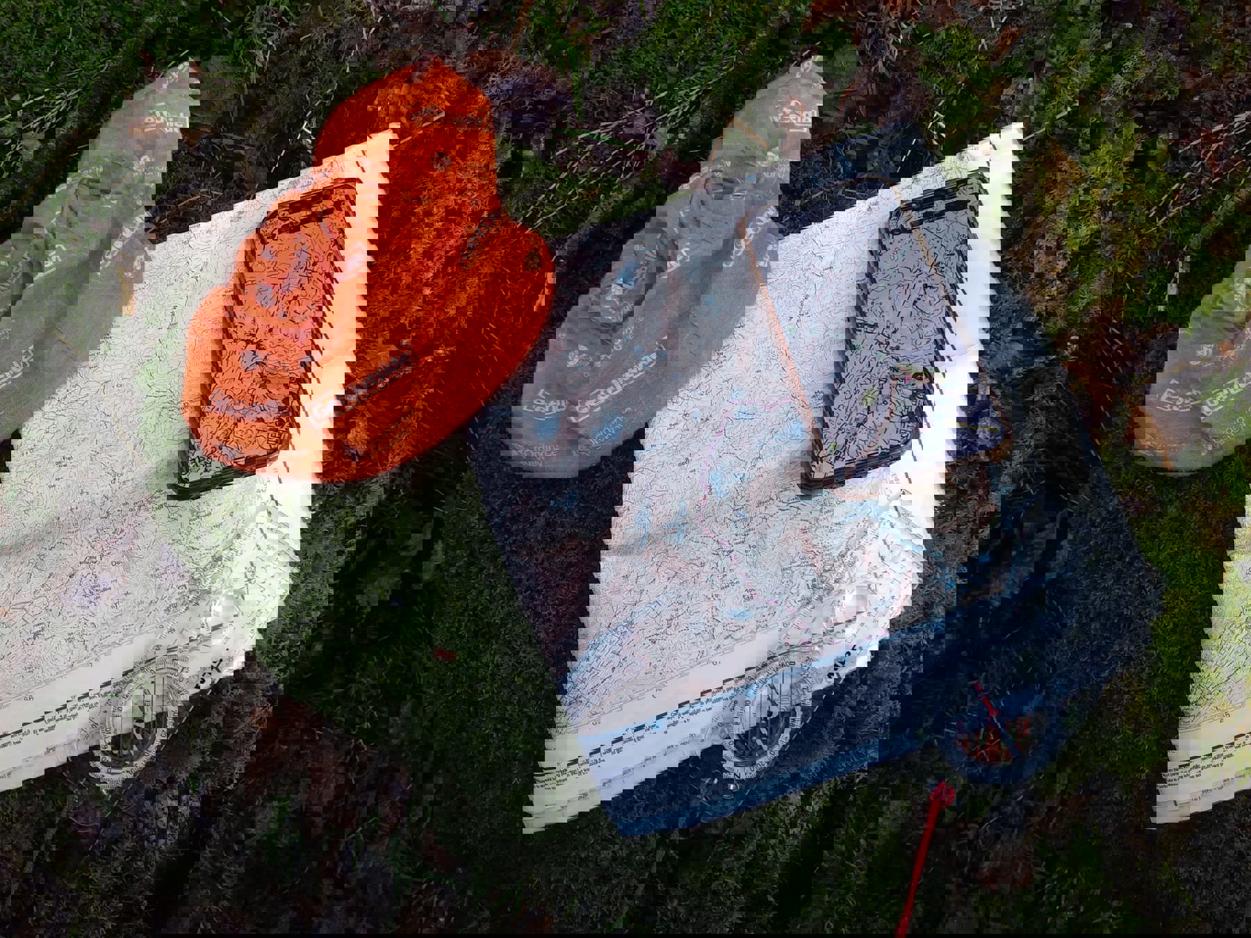 Mahroof’s map is on the ground, on top of some moss, levaes and bark. His compass and phone, with the digital mapping app open, are led on top.