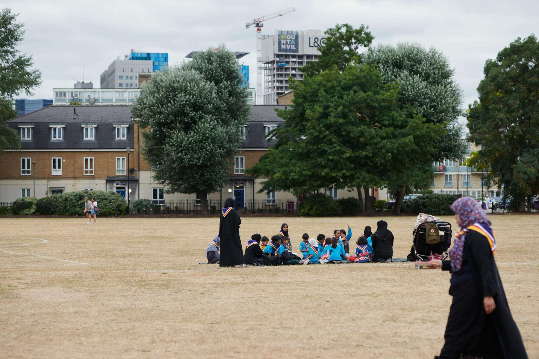 A group of Beavers and volunteers sitting on the ground in a park.