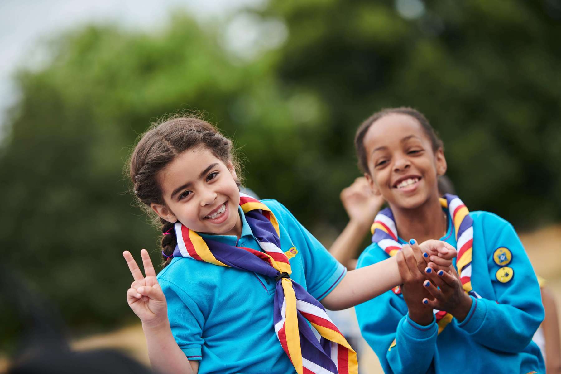 Two Beavers in blue jumpers smiling while one holds up a peace sign.