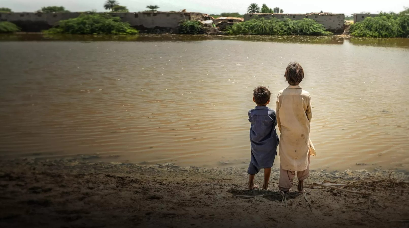 Two children looking out over a muddy lake