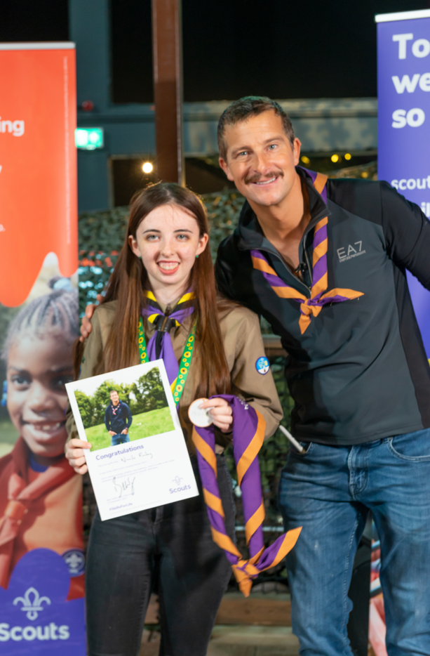 Bear Grylls poses with an Explorer while holding up a certificate.