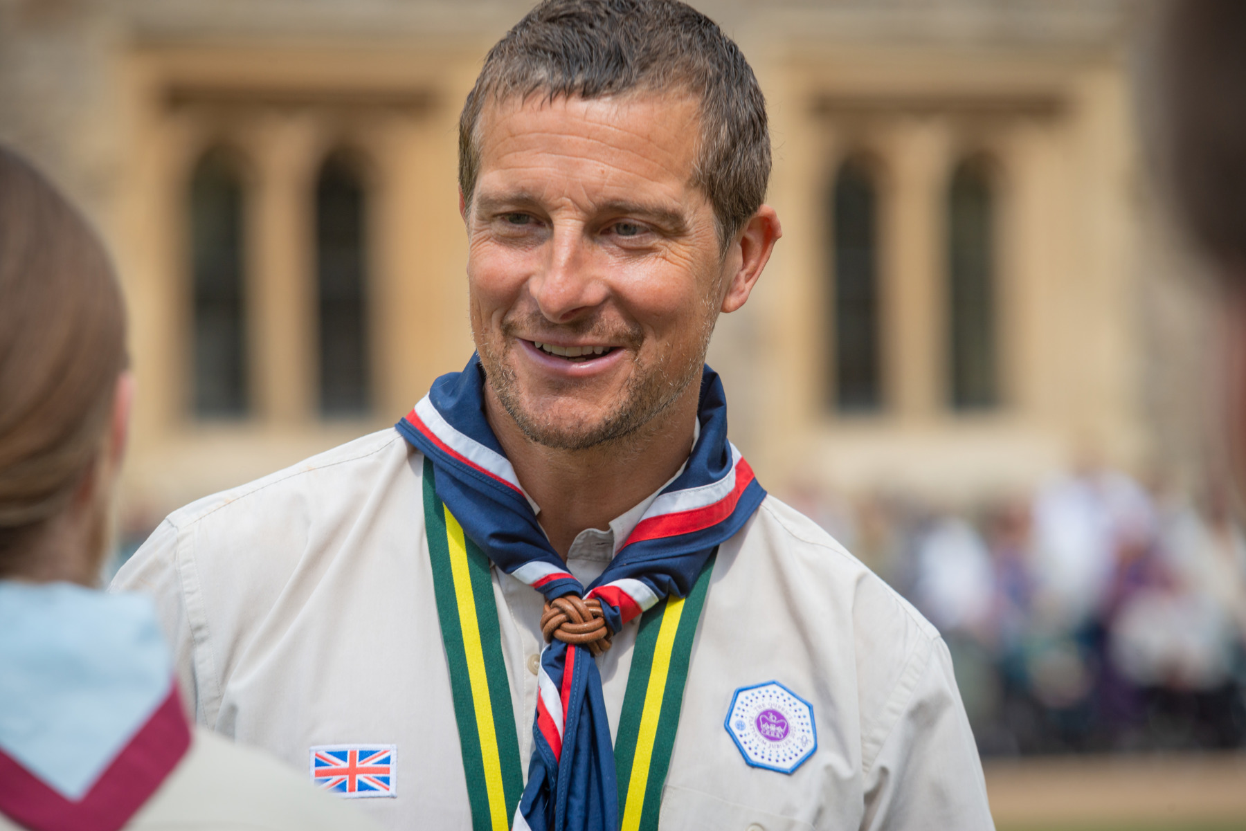 Bear Grylls smiles wearing Scouts uniform with necker and badge