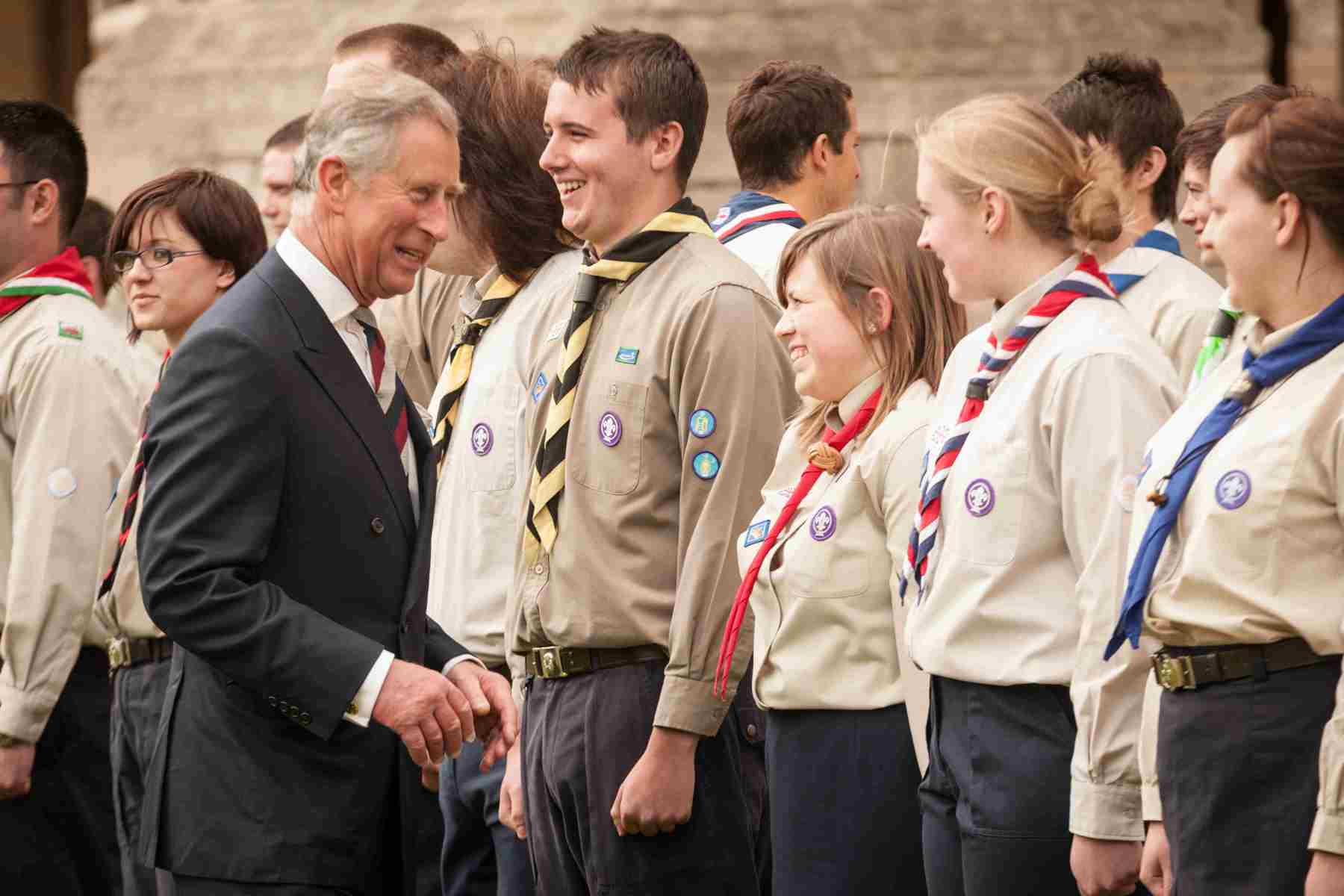 King Charles in a black suit greeting Scouts