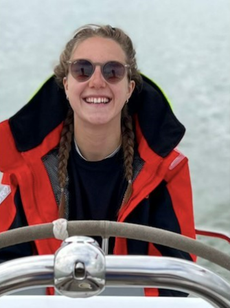 Megan Richardson wearing sunglasses on a boat smiles at the camera 