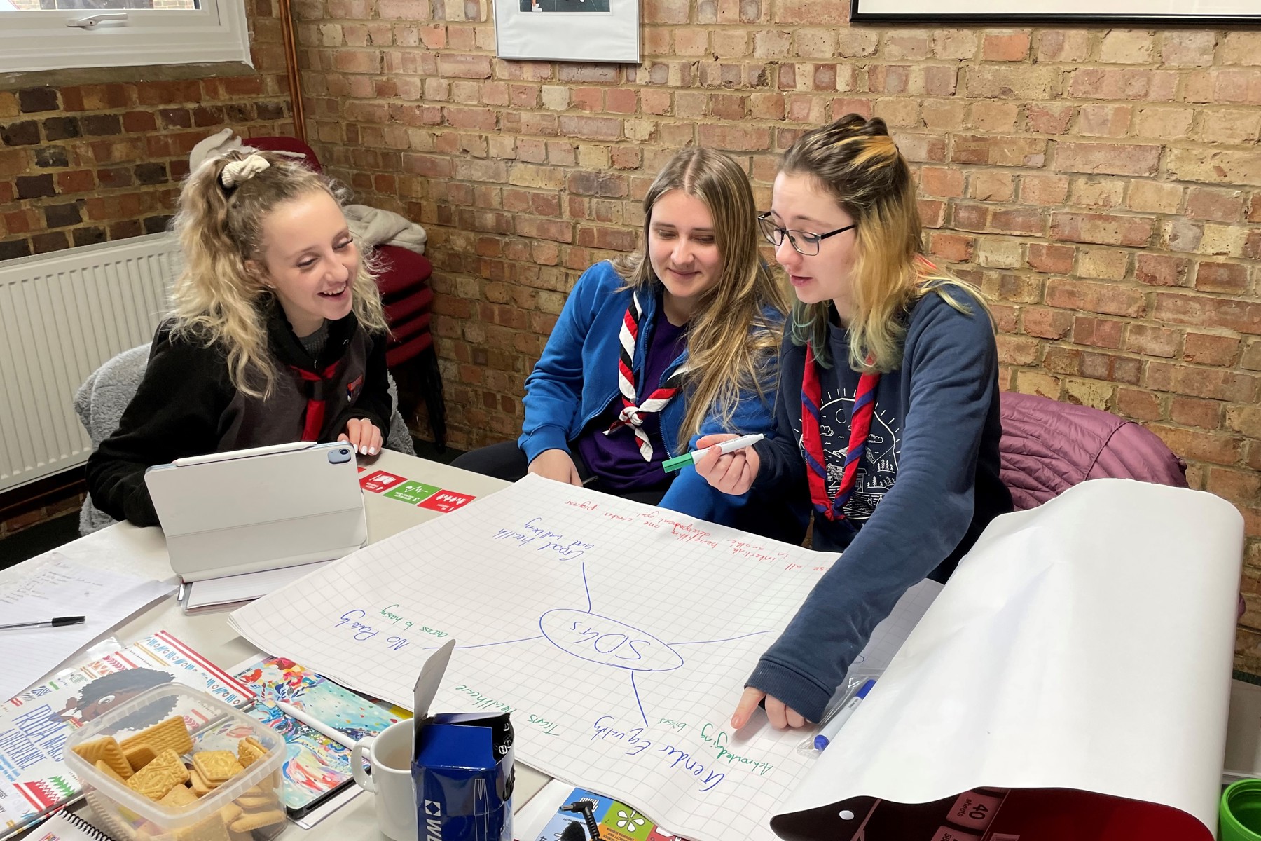 Three female Scouts sitting at a table working on a mindmap to plan an event