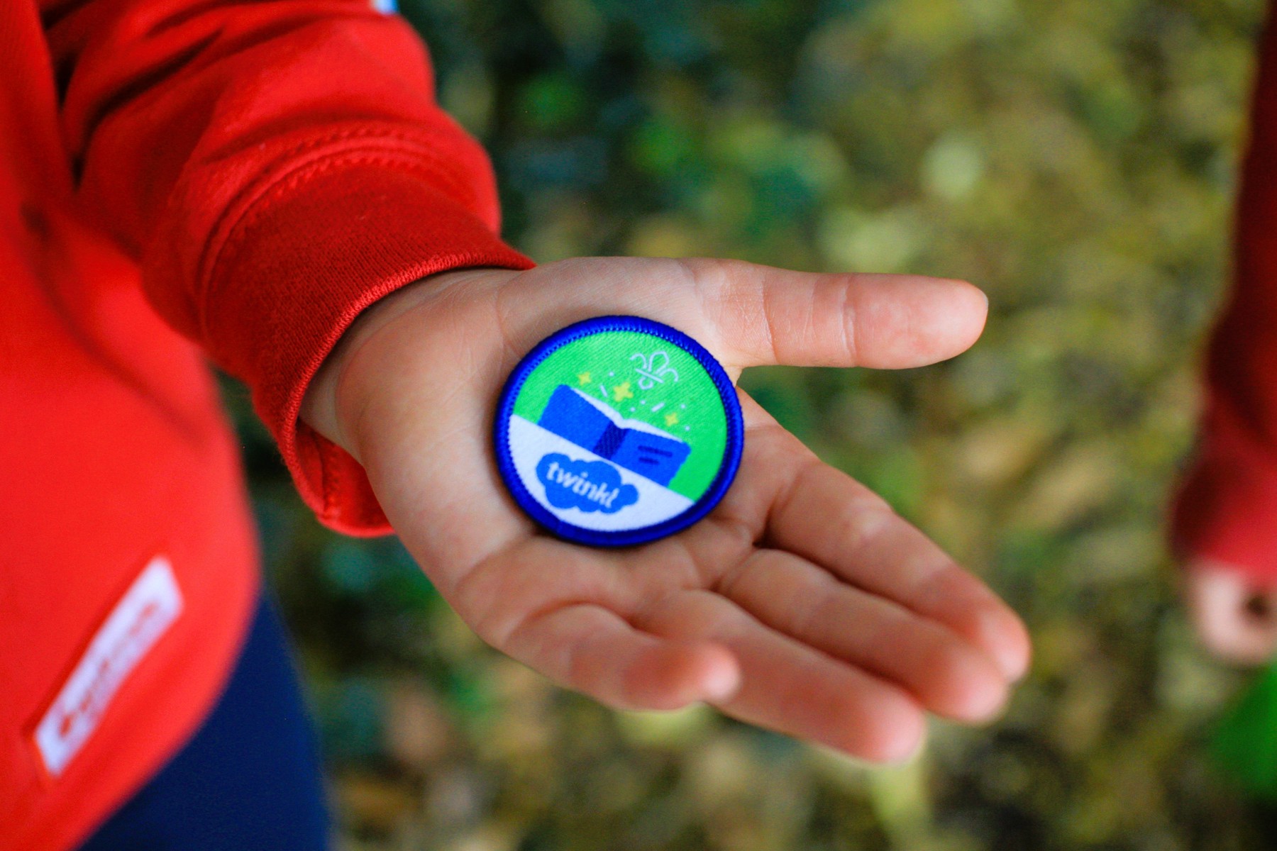 Squirrels story time badge being held by a young person