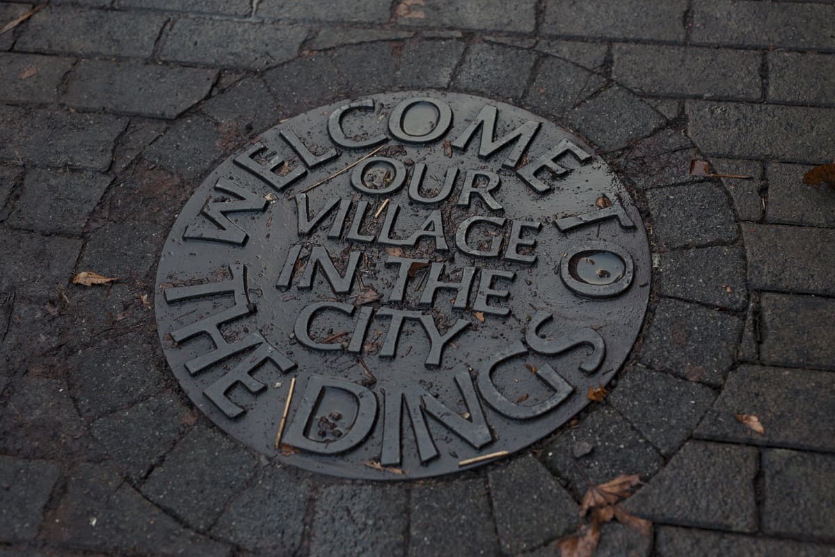 A plaque on the floor reads "welcome to the Dings, our village in the city"