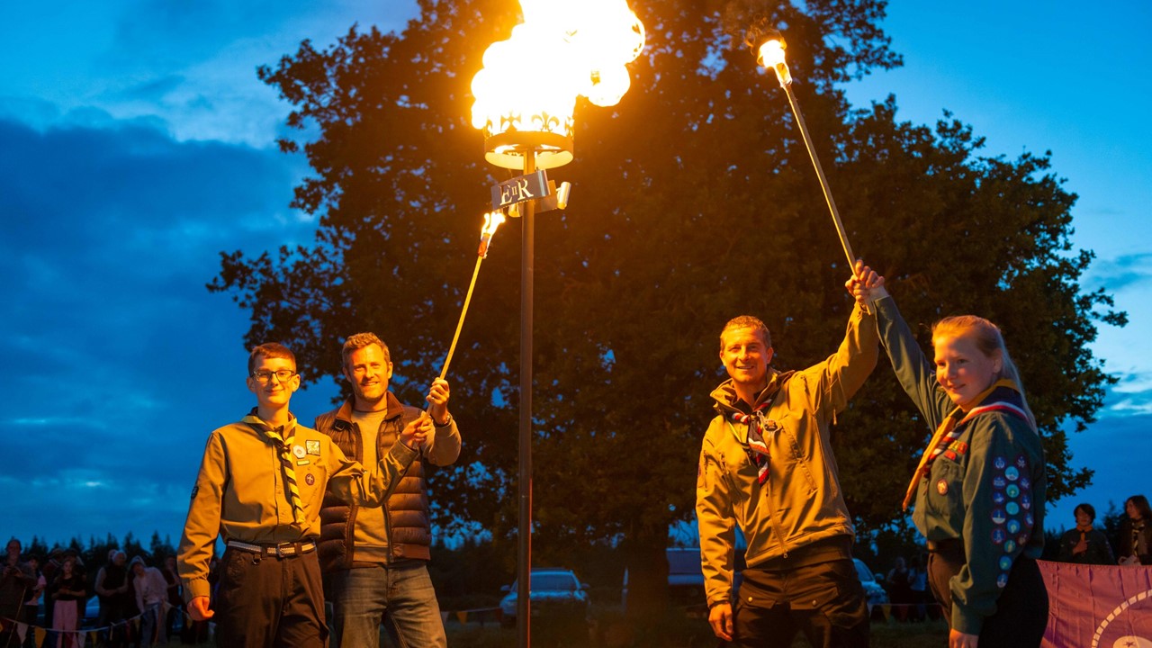 Chief Scout Bear Grylls lighting a jubilee beacon with three other Scouts