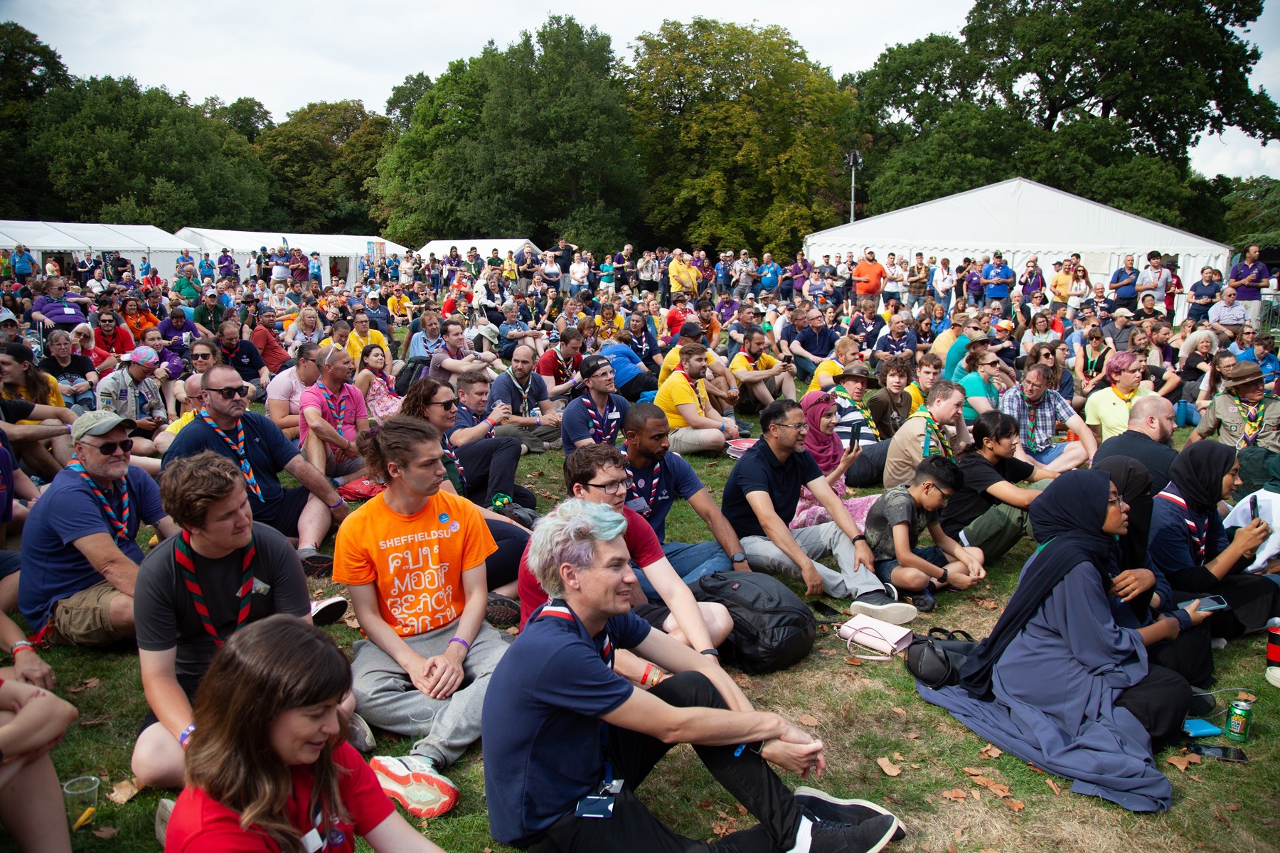 Gilwell Reunion attendees sitting on the ground outside.