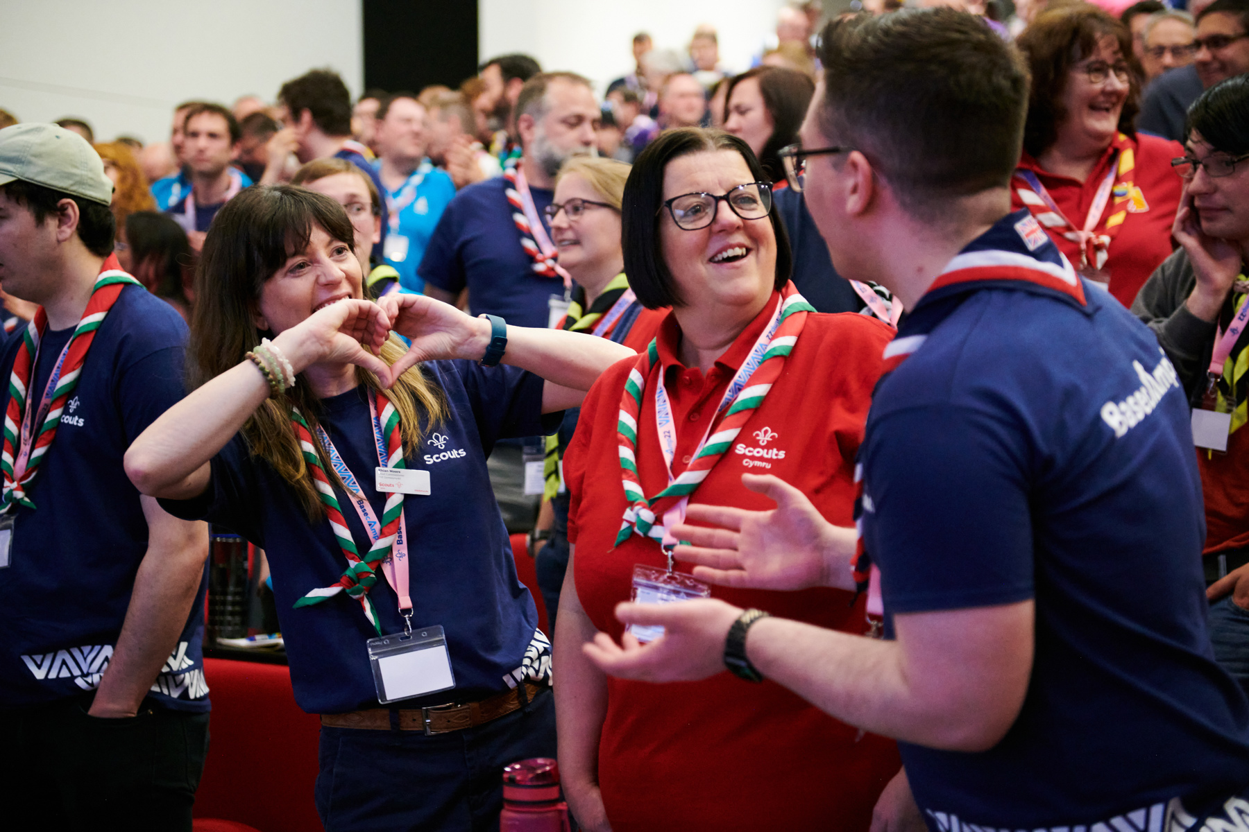 Three volunteers are chatting, one of them is making a heart shape with their hands.