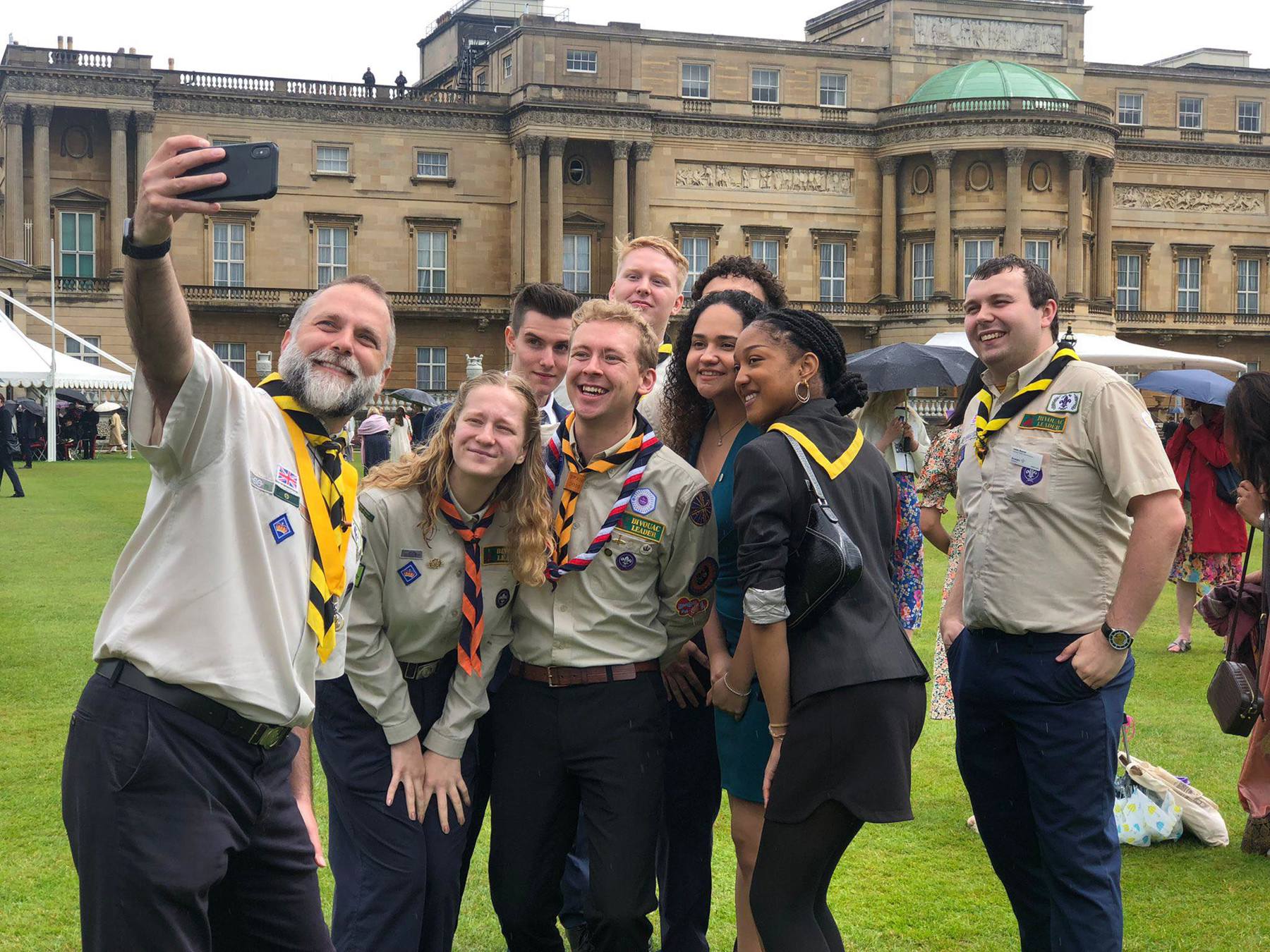 A group of volunteers in uniforms take a selfie outside.