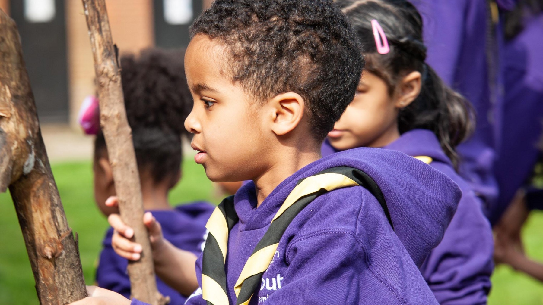 A young child holding on to a stick.