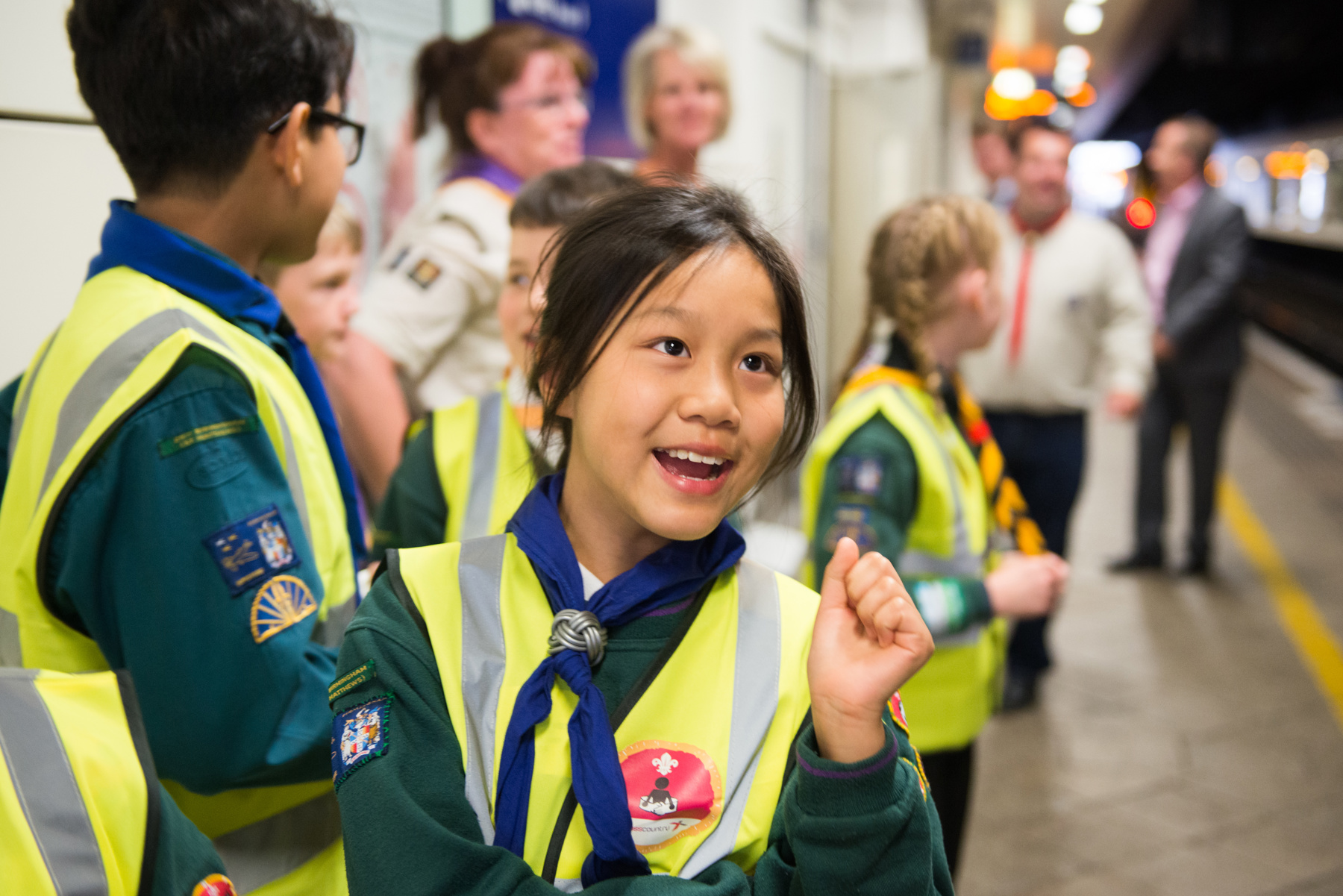 A Scout wearing a high-vis vest at a train platform