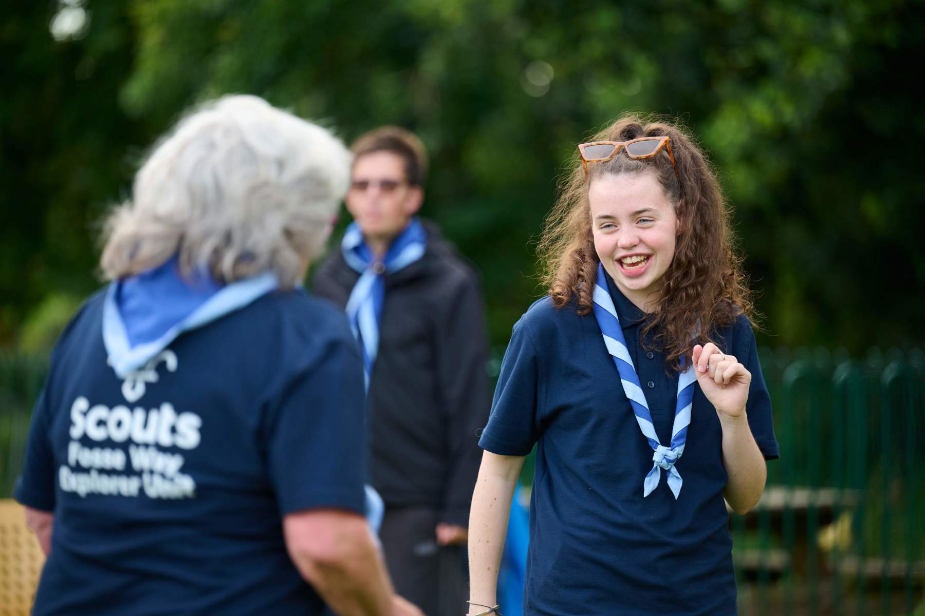A young person wearing a blue necker smiles at a volunteer.