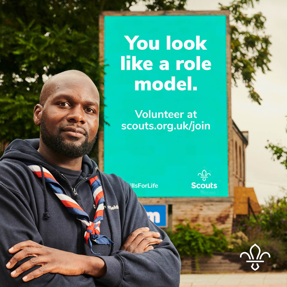 Dwayne Fields standing in front of a Scout banner that says "You look like a role model.'