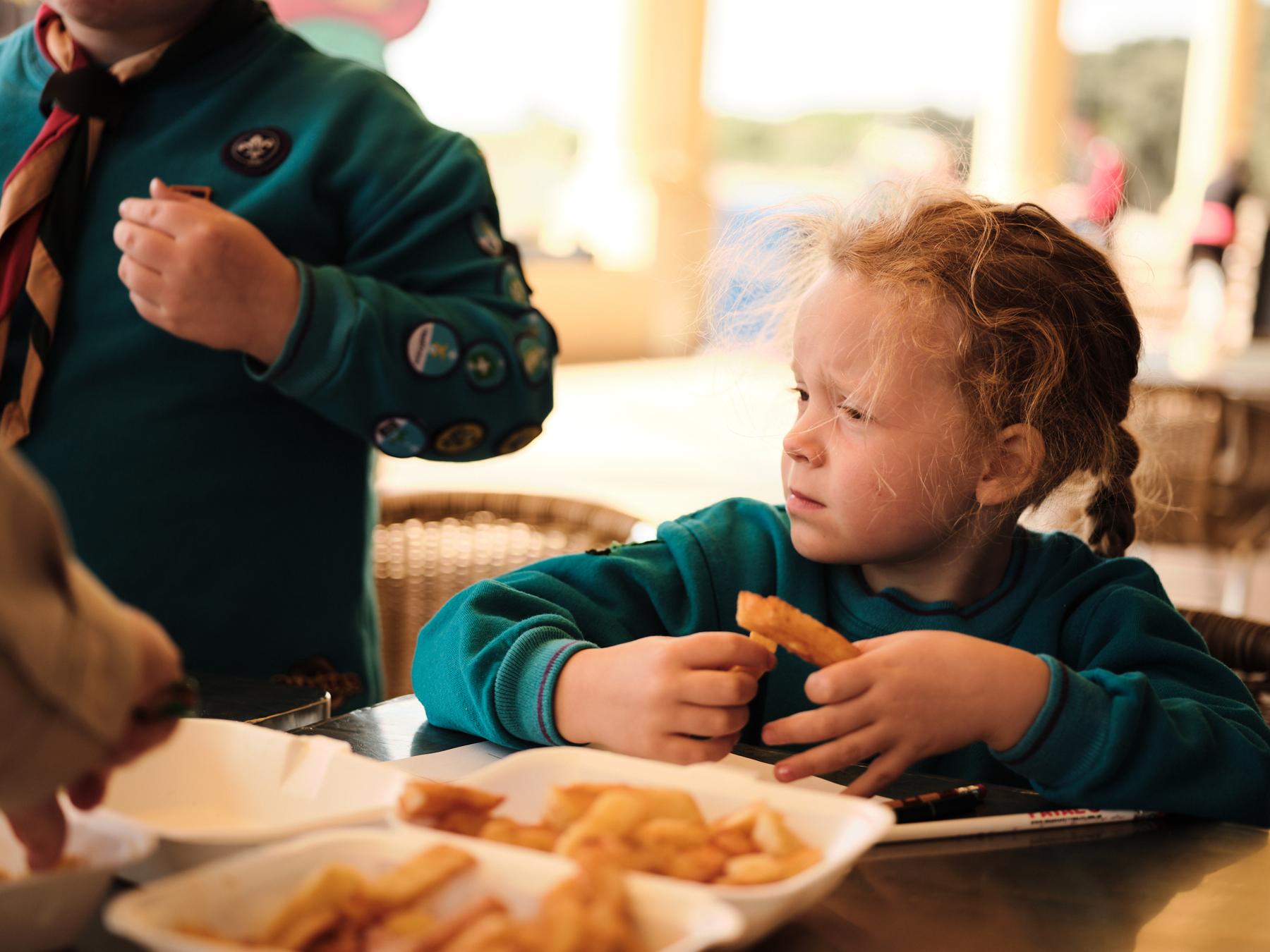 A group of Beavers are sharing a box of chips, passing them across the table to each other.