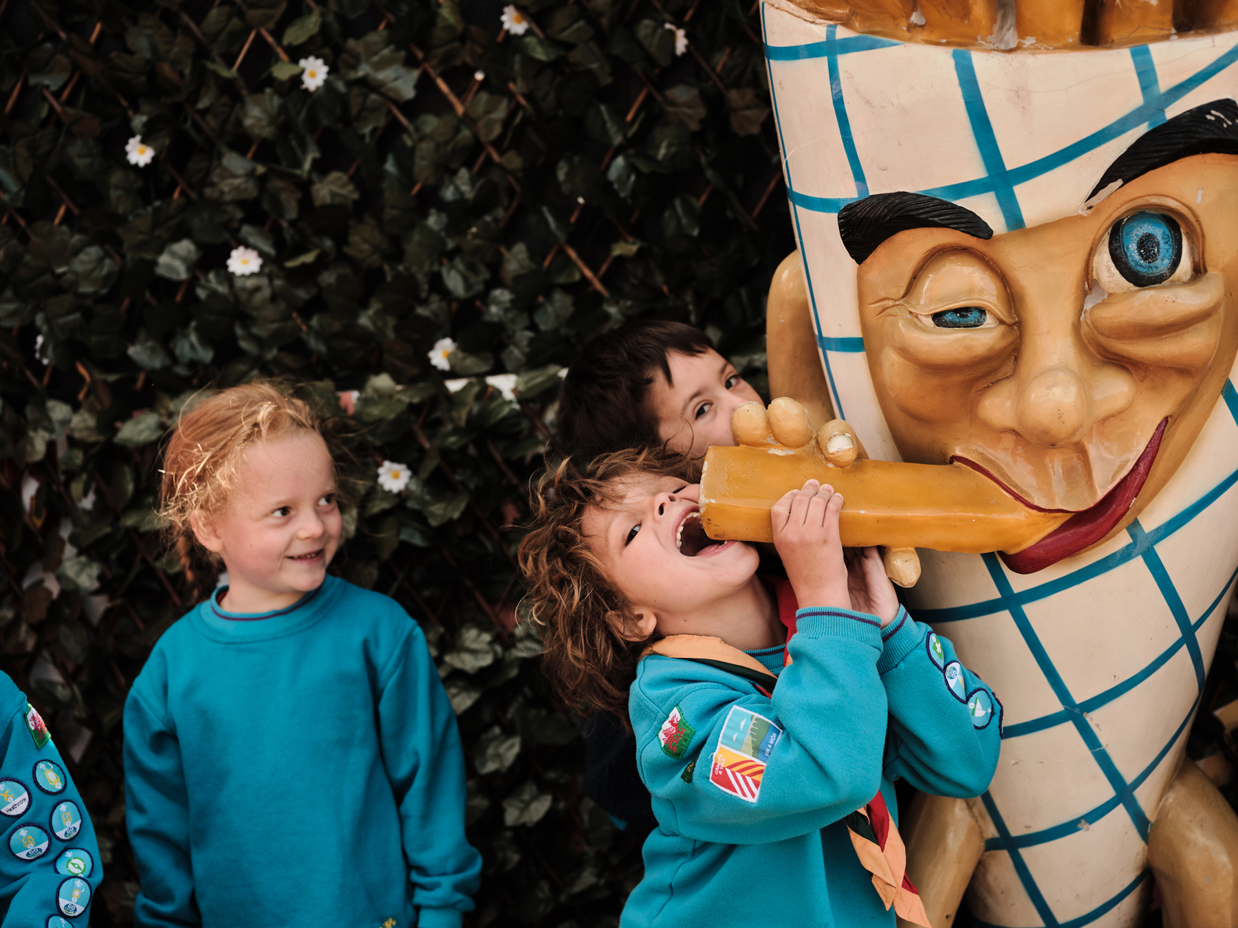 Four Beavers pose for a photo with a statue of a giant cone of chips. One of the Beavers is leaning up on his tip toes with his mouth wide open, pretending to eat the statue.