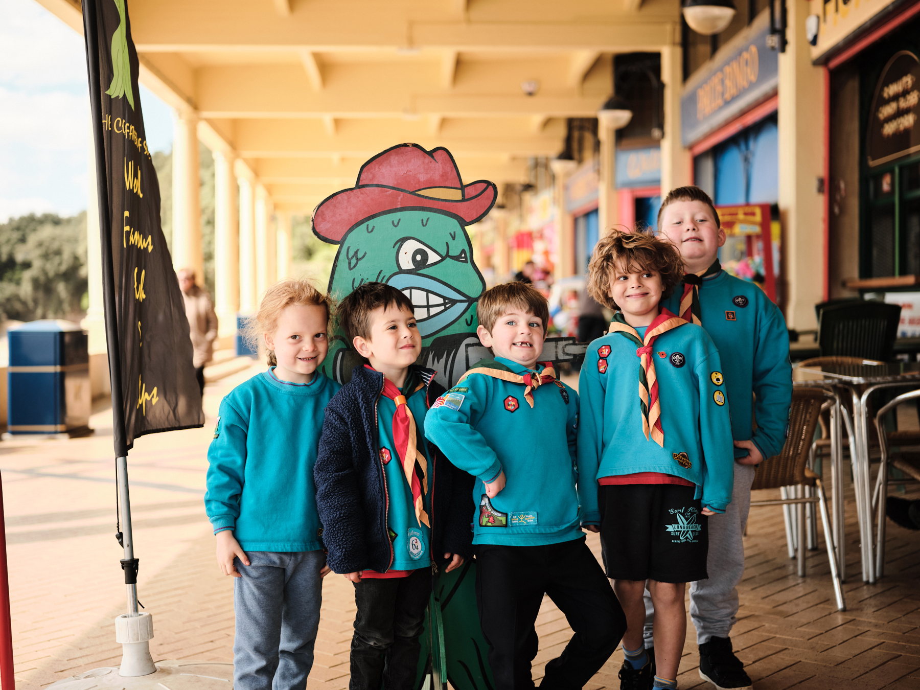 Five Beavers pose with a chip shop mascot for a photo. They're smiling and pulling silly faces at the camera.