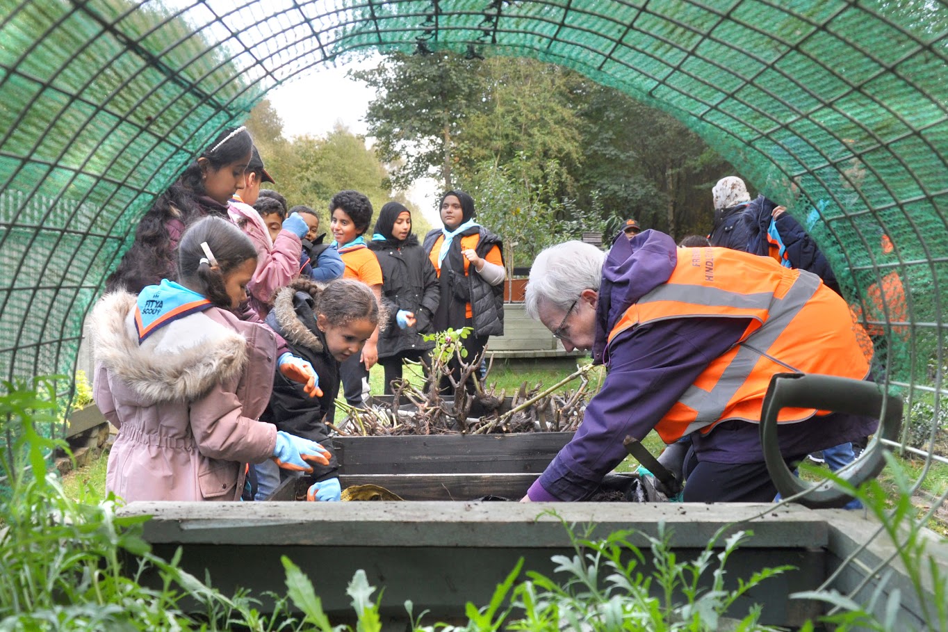 Three young people help a volunteer with planting