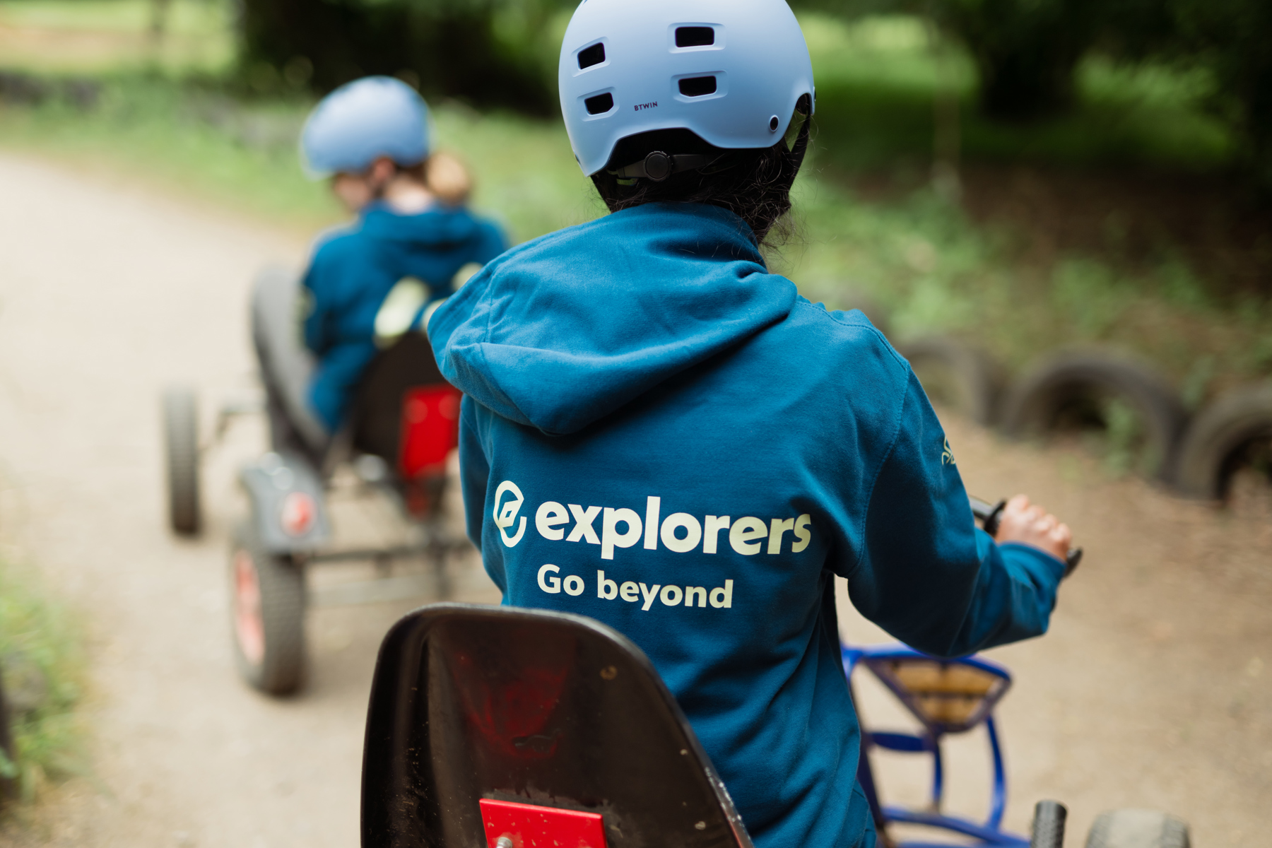 The back of a person wearing an Explorers hoodie and helmet while karting.