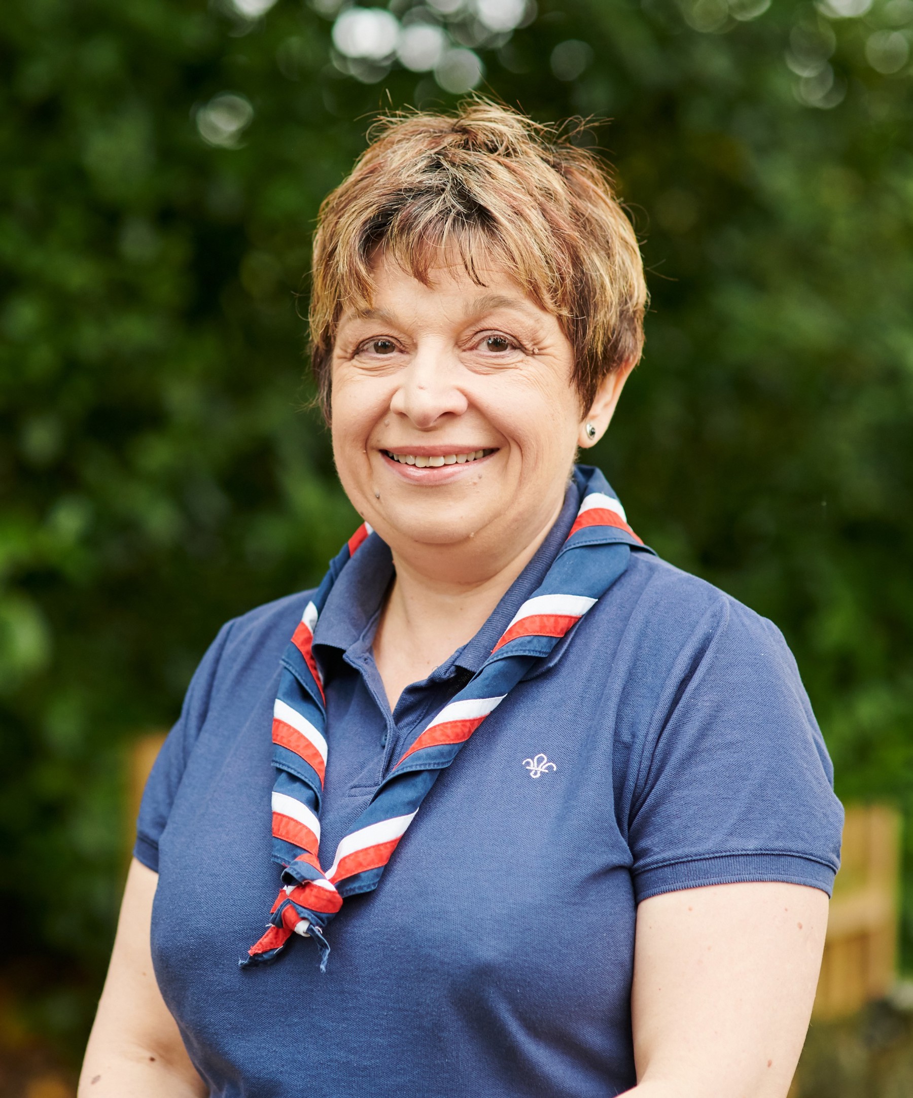 Susan Harris smiling at the camera wearing a navy polo shirt and stripy scarf