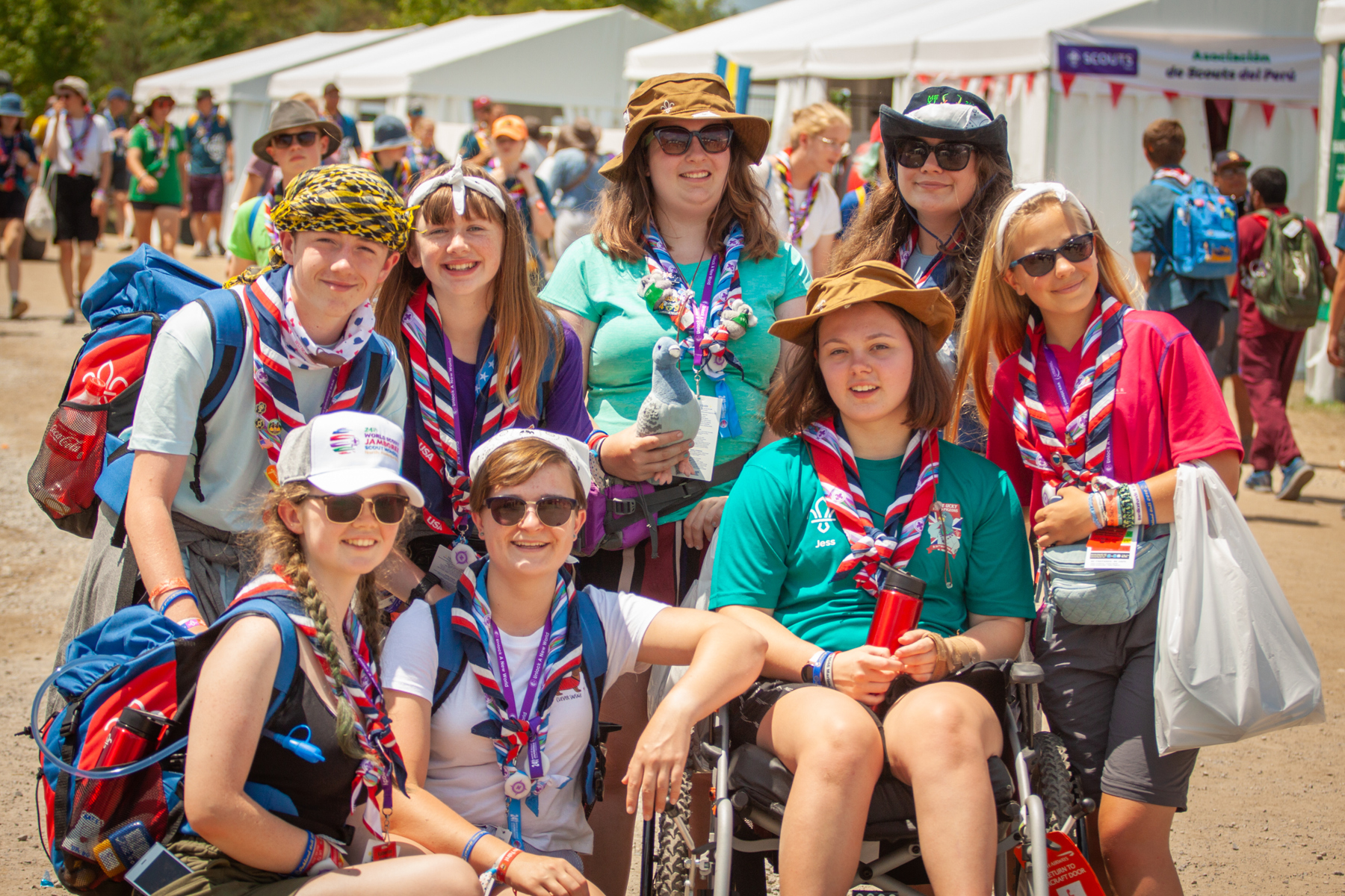 A group of explorers at a Jamboree. They are all smiling and wearing neckers, stood together and looking at the camera.