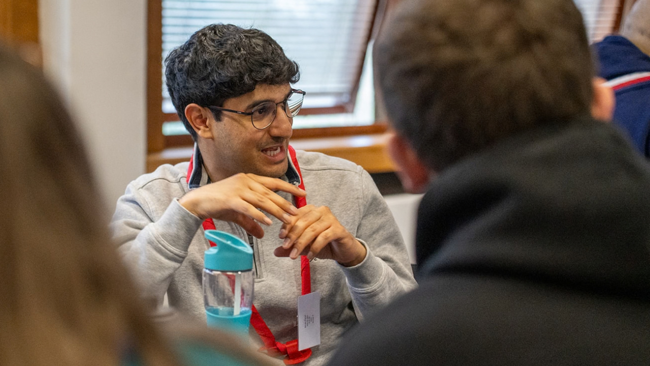 A man sat at a table with other volunteers, mid conversation