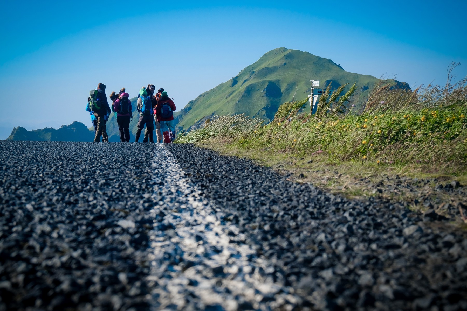 A group of people dressed for hiking are stood against the backdrop of mountain scenery