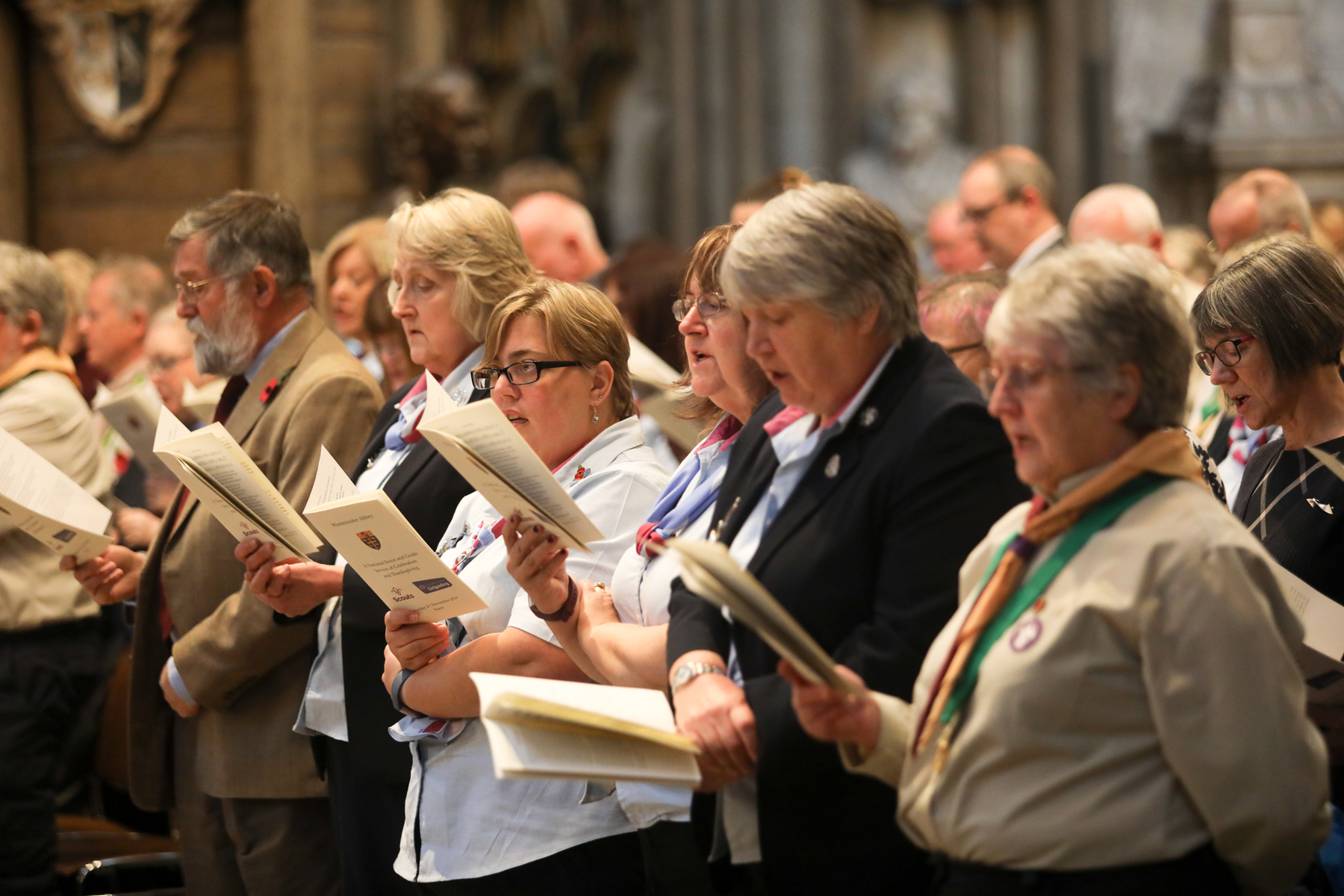 A row of Scouts singing from a leaflet during Thanksgiving service.