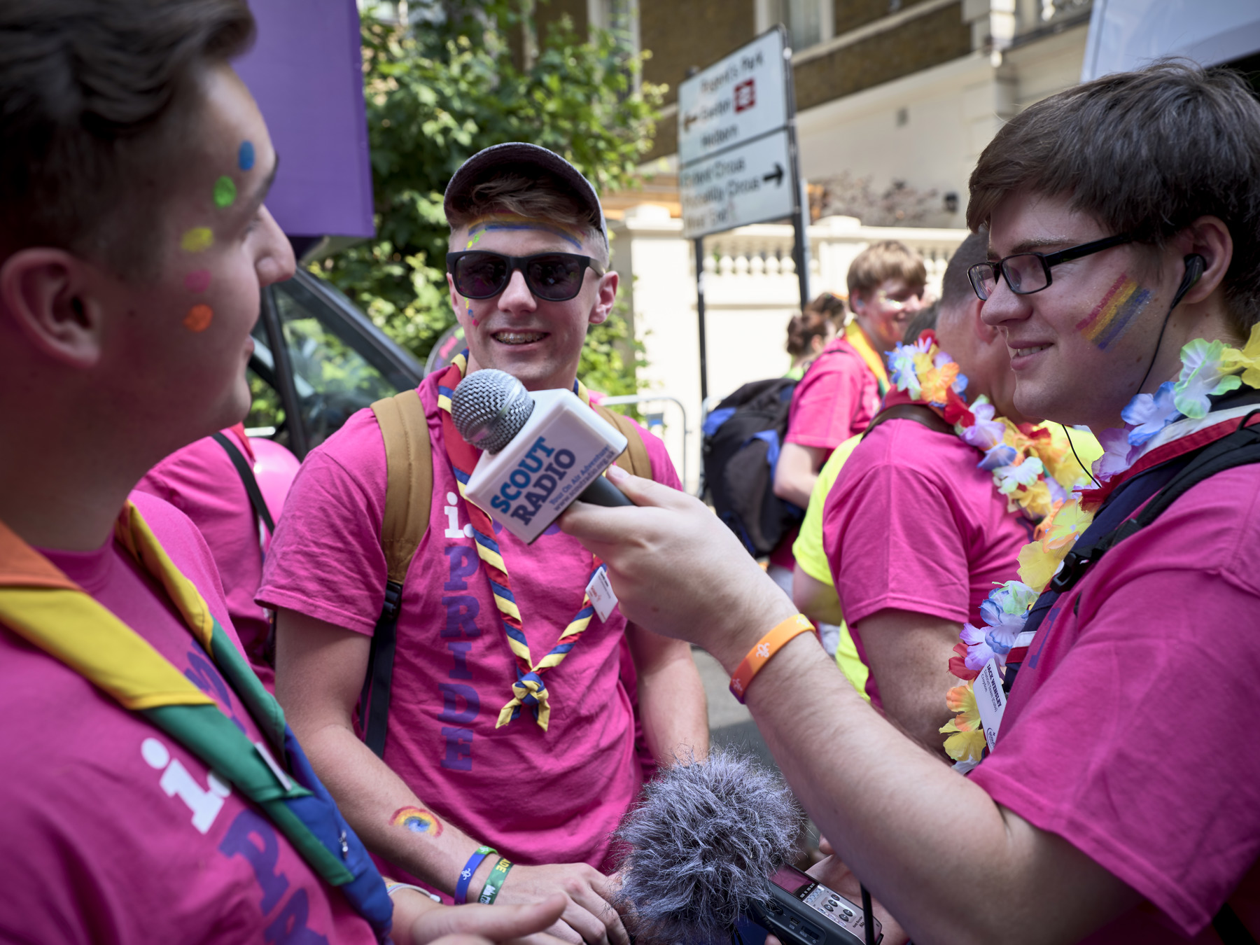 A volunteer holding a Scout Radio microphone points it at another volunteer at a Pride Parade.