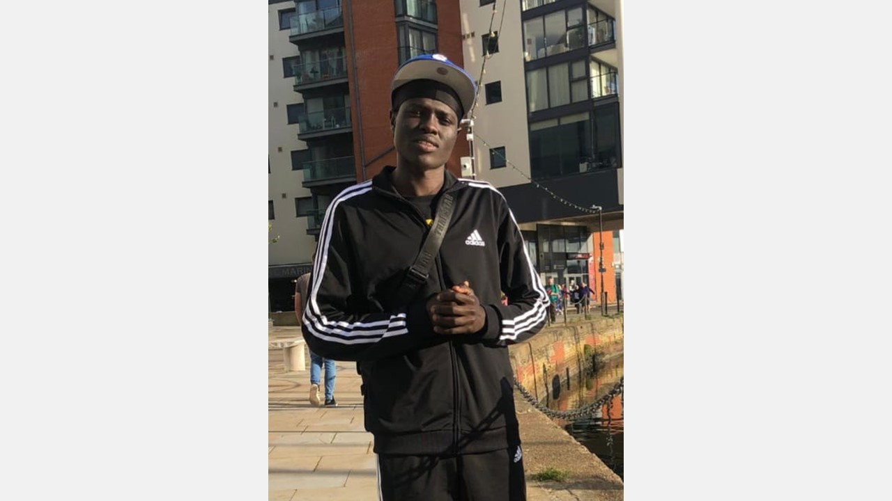 A young person wearing a black tracksuit and hat