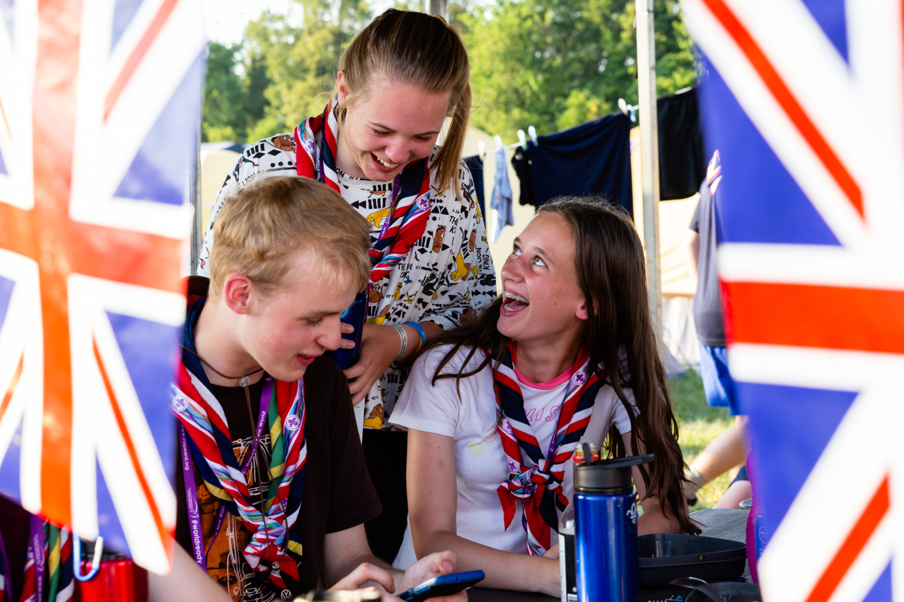 Three young people smiling at international camp surrounded by British flags
